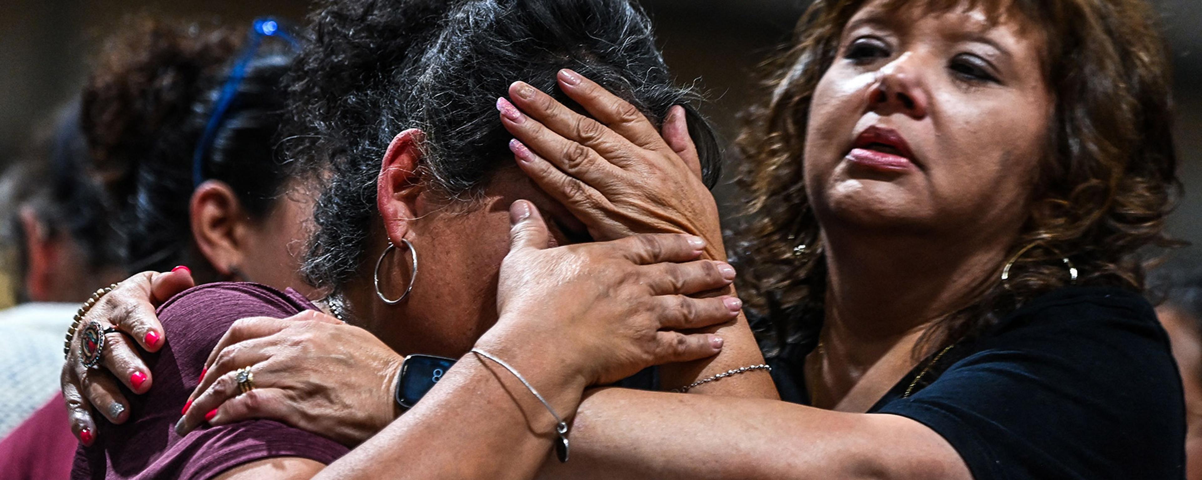 A close-up shot of one woman holding and comforting another grief-stricken woman
