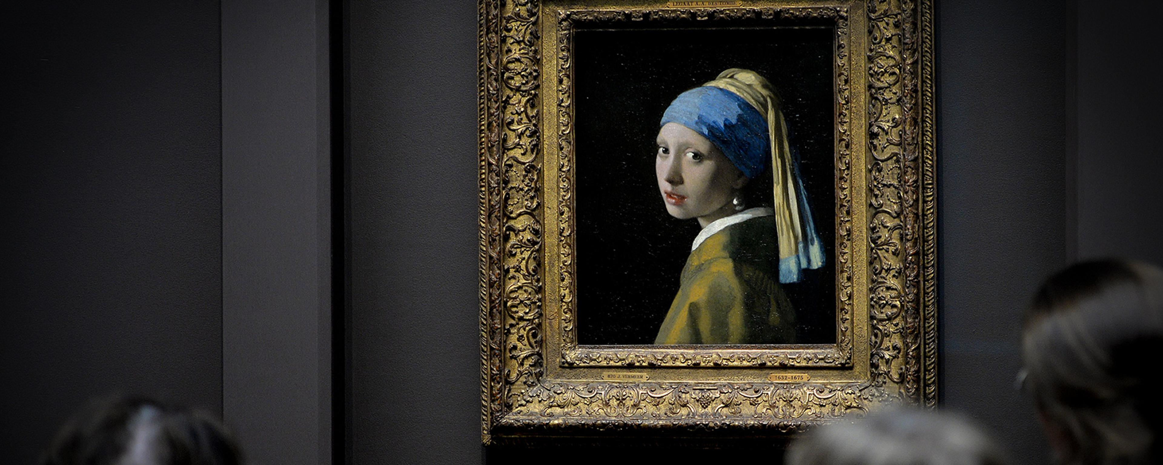 Painting of a girl with a pearl earring in an ornate frame, viewed by three people in a gallery setting.