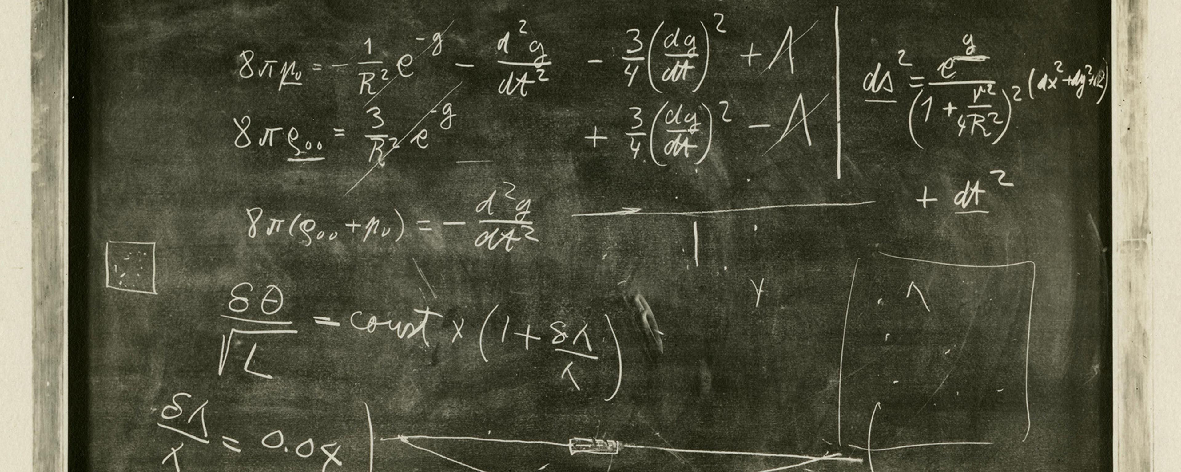 Black and white photo of a chalkboard filled with complex mathematical equations and diagrams.