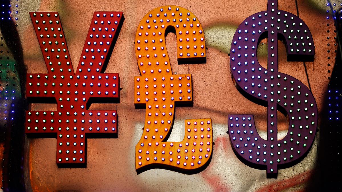 Illuminated currency symbols yen, pound and dollar in red, orange and purple on a textured background.