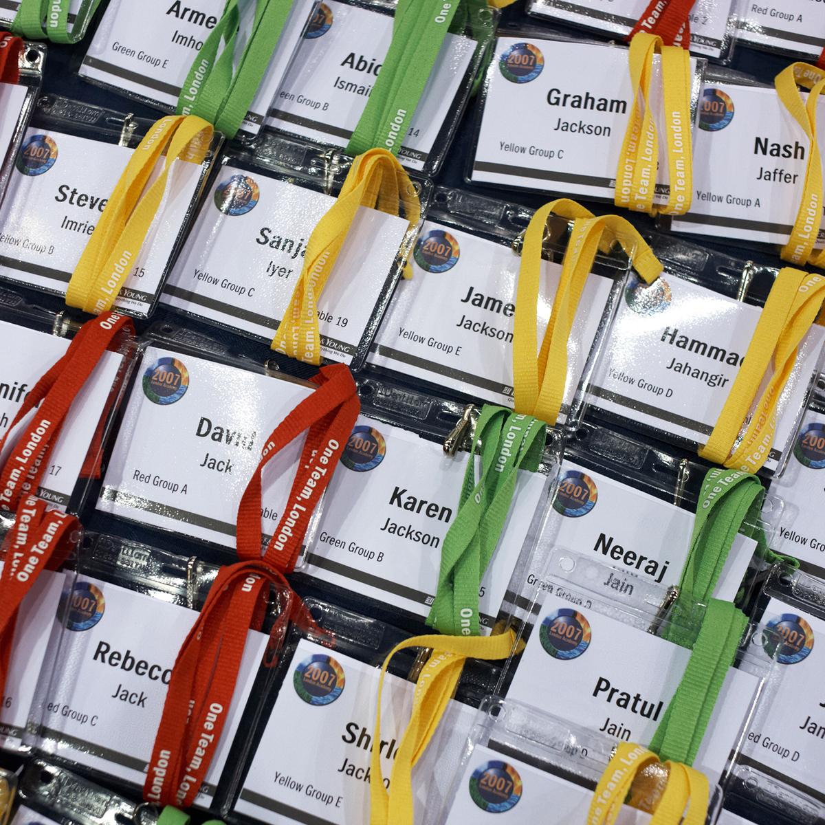 Photo of various name badges with colourful lanyards laid out in rows for an event or conference.