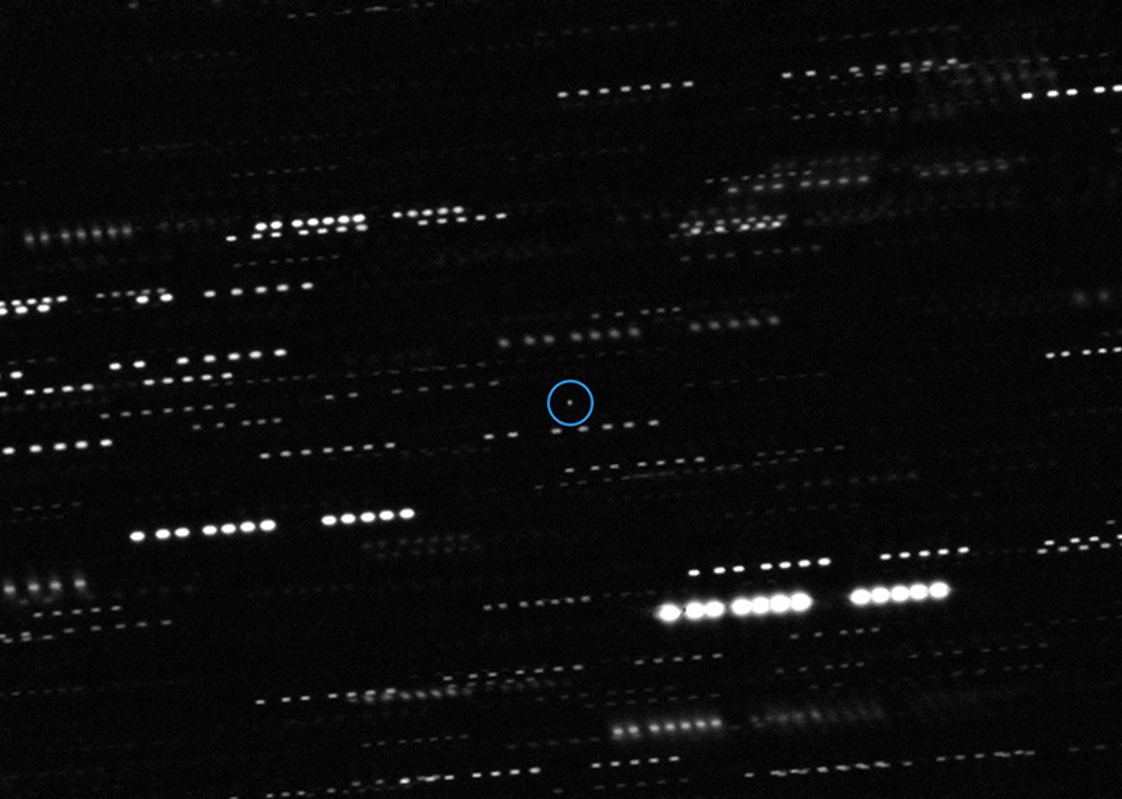 Photo of a starry night sky with streaks of light and a small circle highlighting an object in the centre.