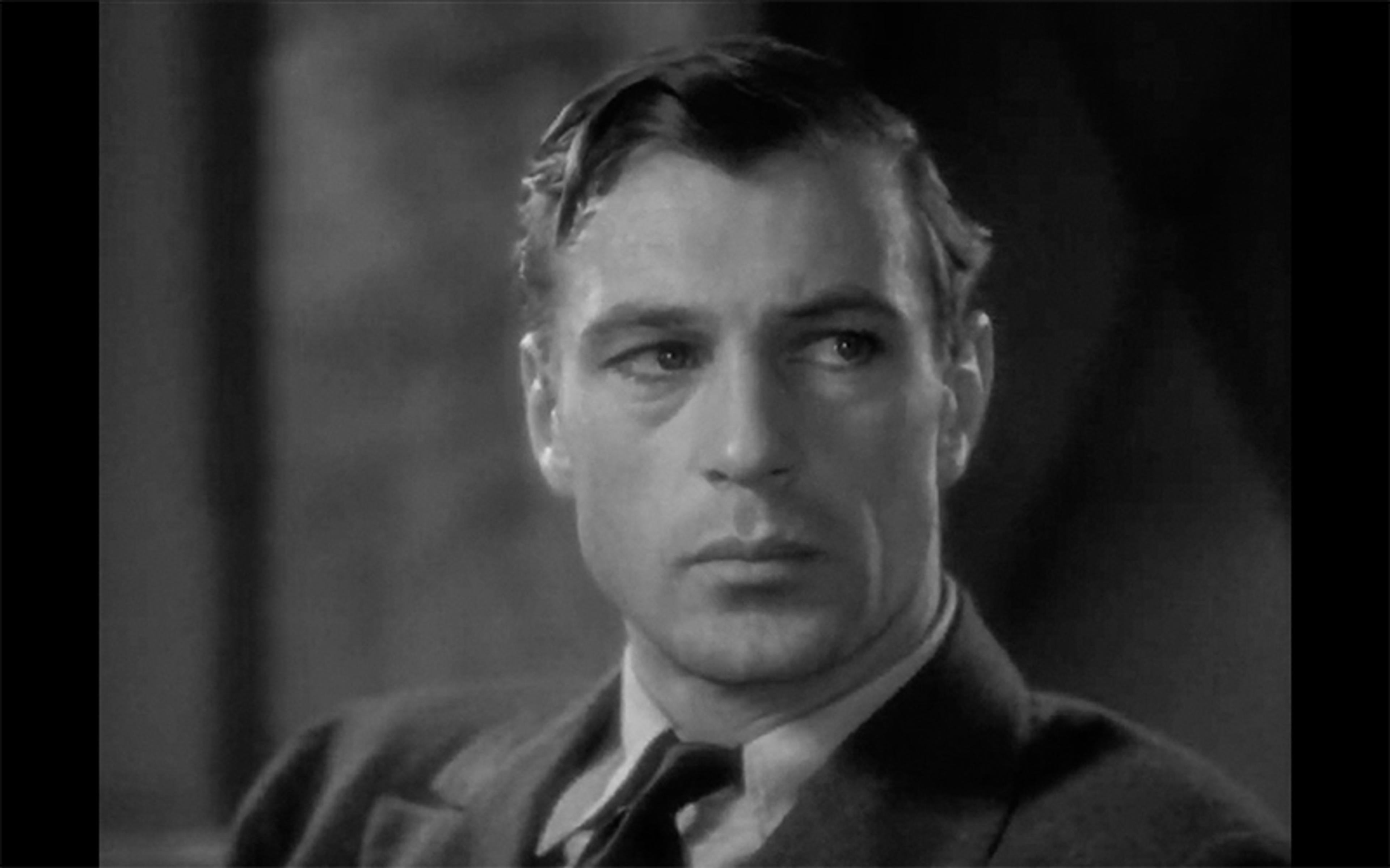 Black and white photo of a man in a suit looking to the side, with a serious expression, dressed in the style of the 1930s.