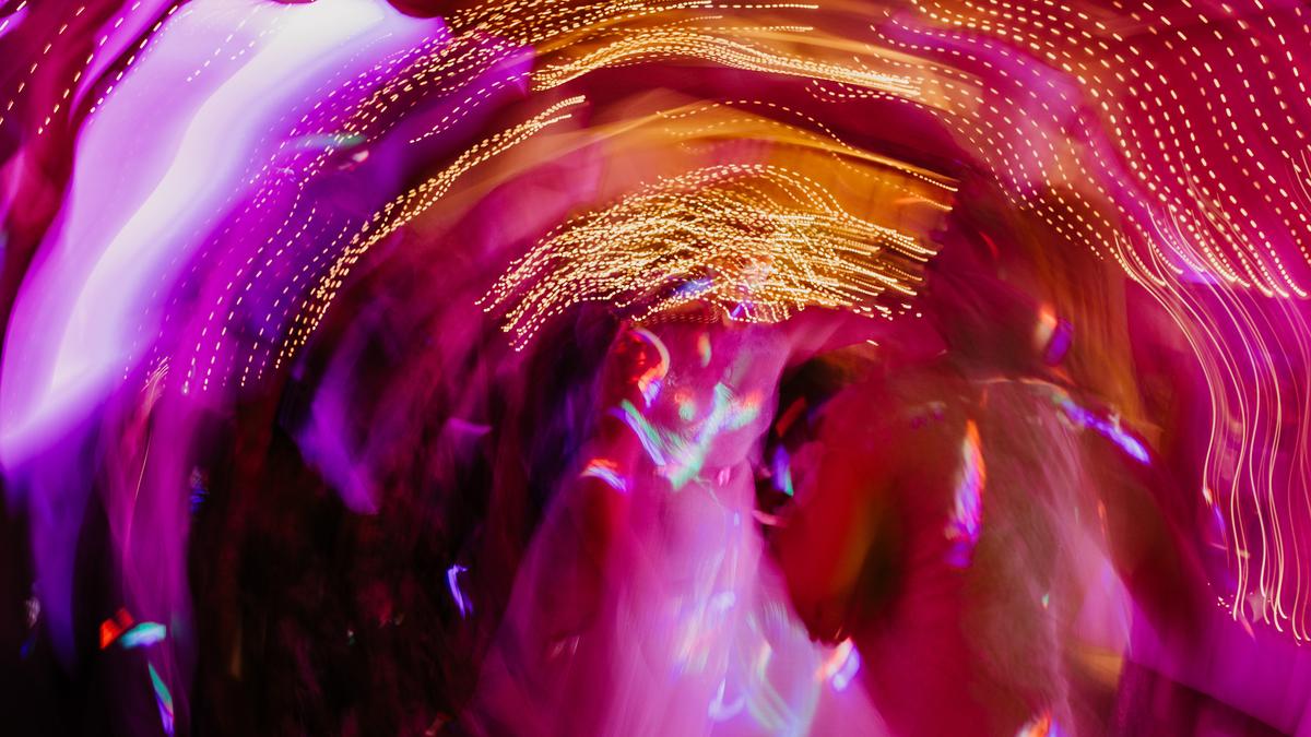 Abstract photo of colourful lights in motion creating a swirl effect with pink, purple and gold hues.