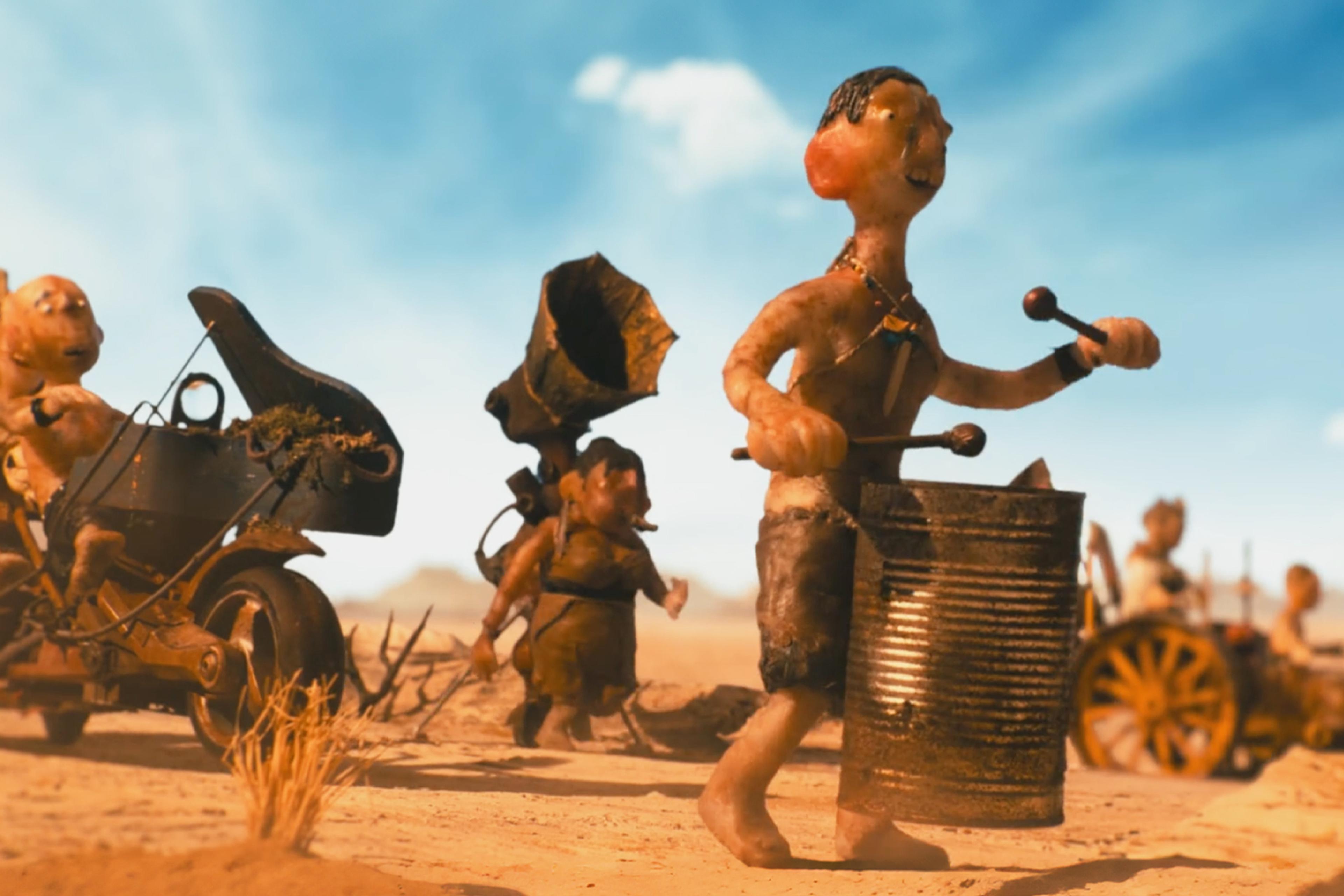 Claymation figures in a desert, including a man drumming on a barrel and others with makeshift vehicles and a gramophone horn.