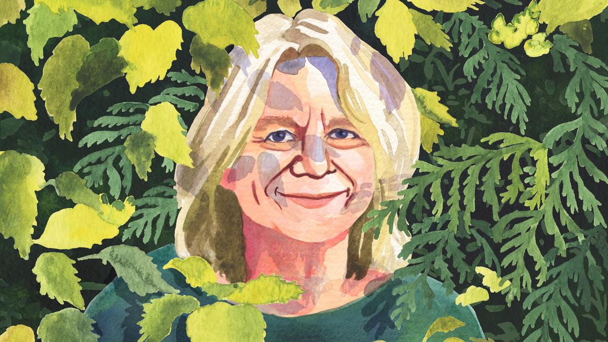 Watercolour painting of a smiling woman with blonde hair surrounded by green and yellow foliage.
