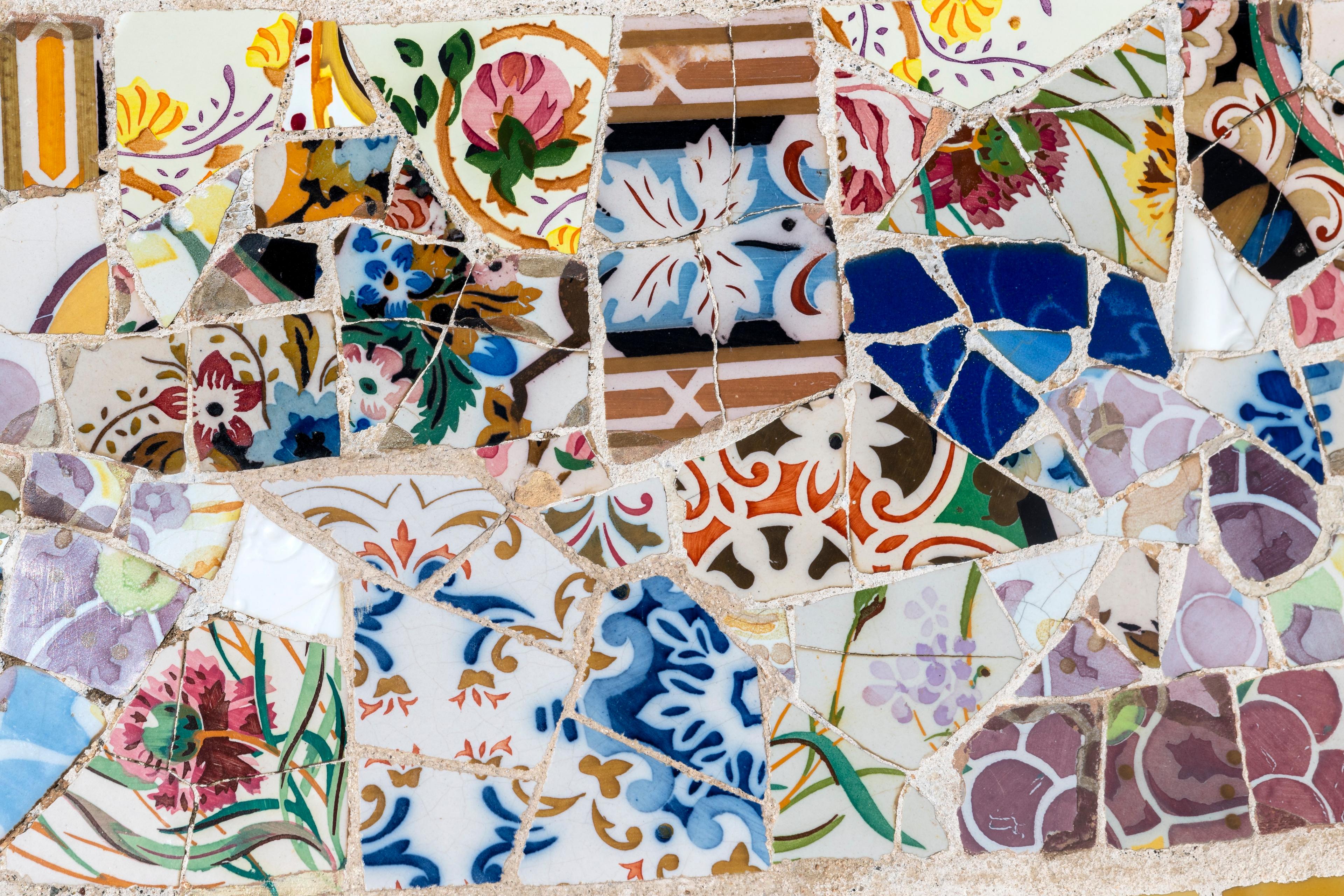 Mosaic art with colourful broken ceramic tiles featuring floral and abstract patterns.