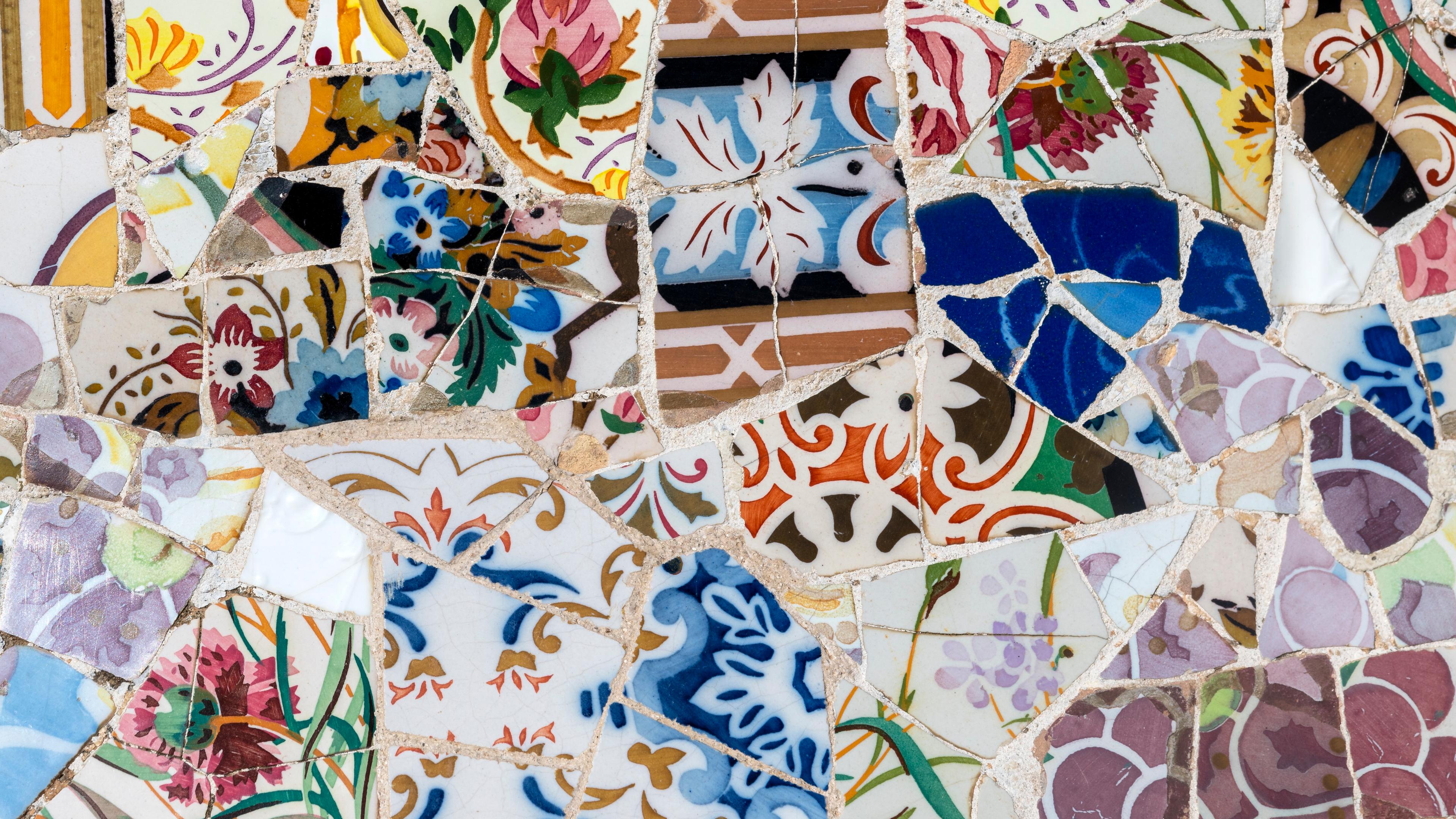 Mosaic art with colourful broken ceramic tiles featuring floral and abstract patterns.