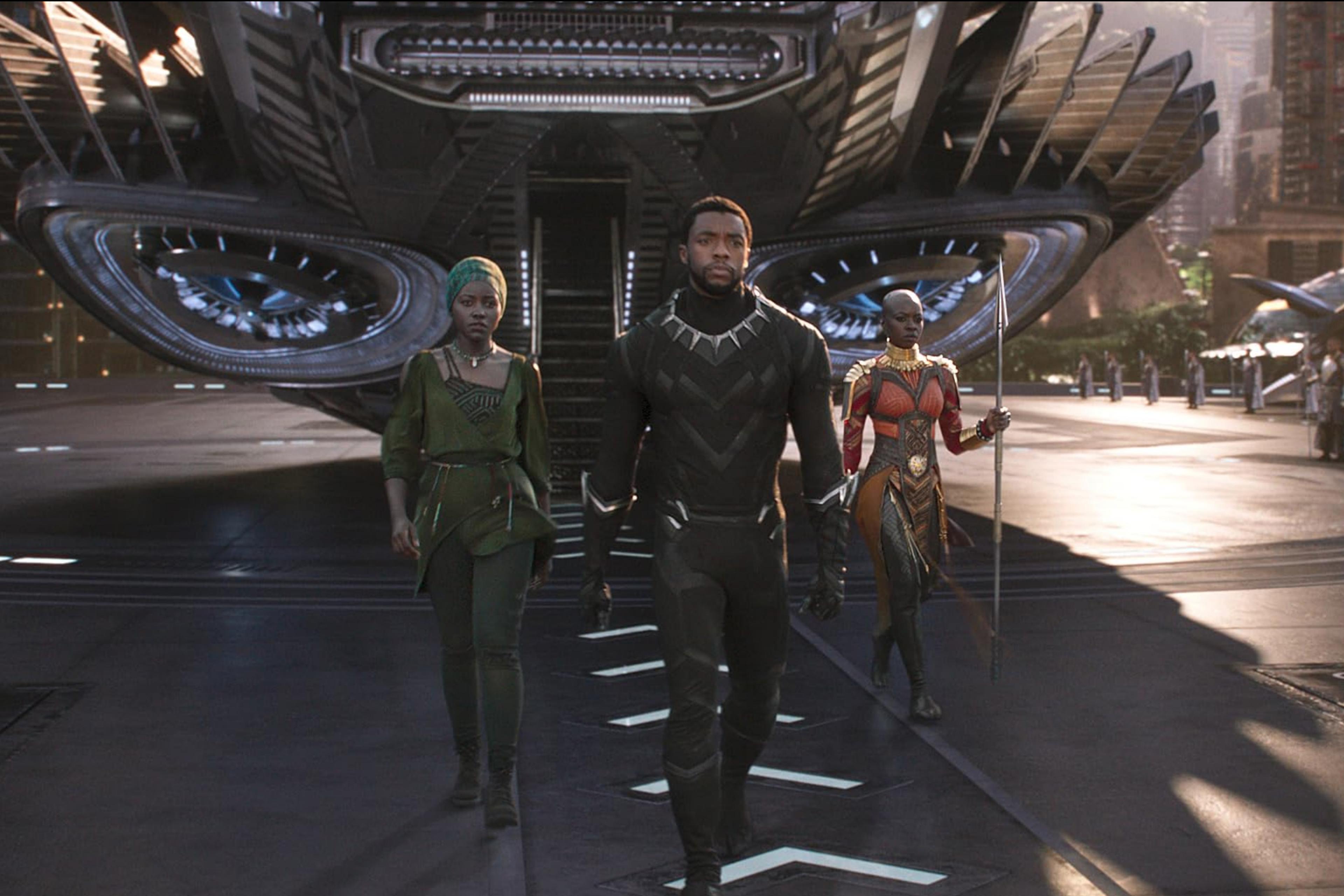 Scene from a film with three characters walking from a futuristic spacecraft in a city setting.