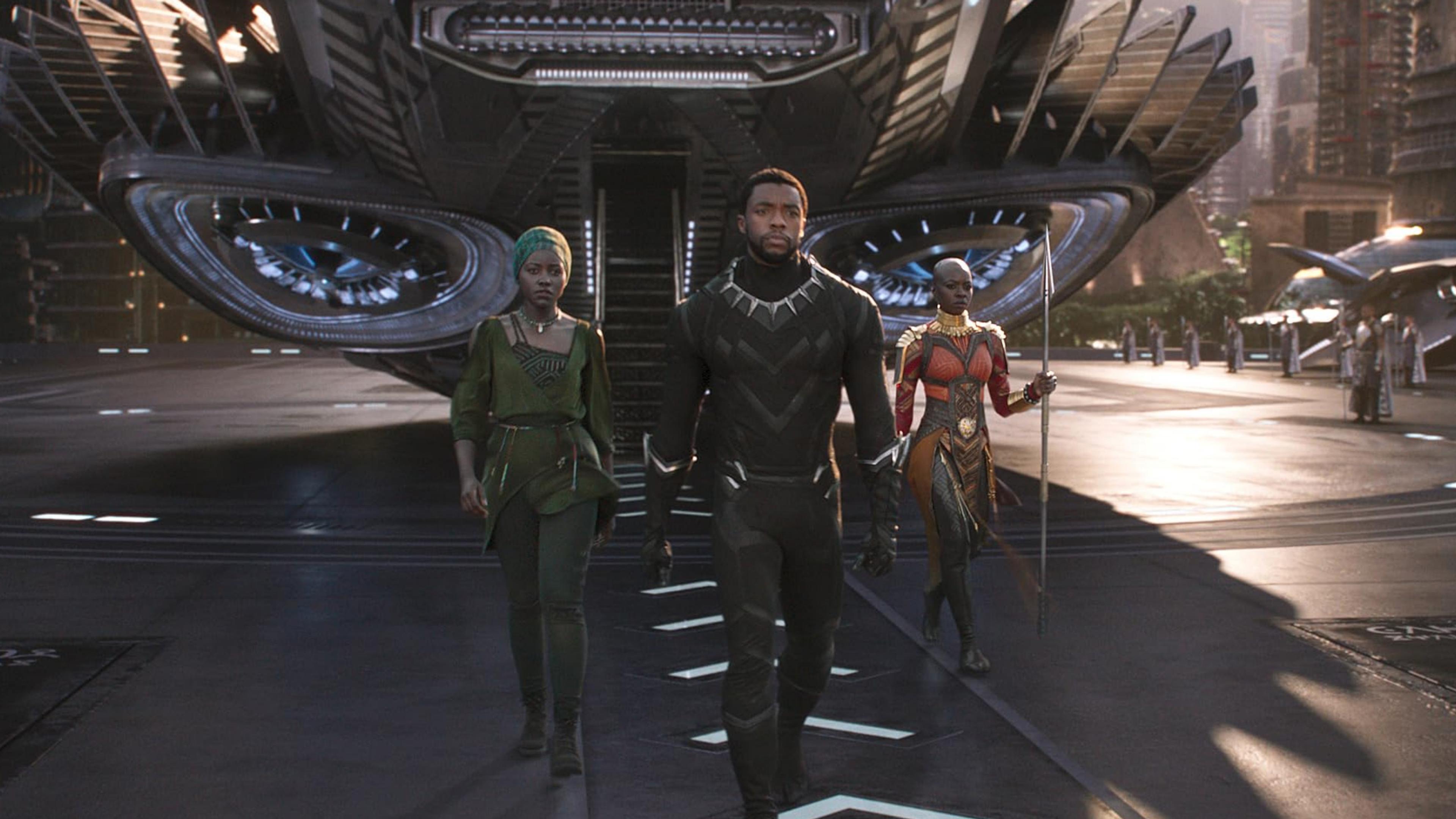 Scene from a film with three characters walking from a futuristic spacecraft in a city setting.