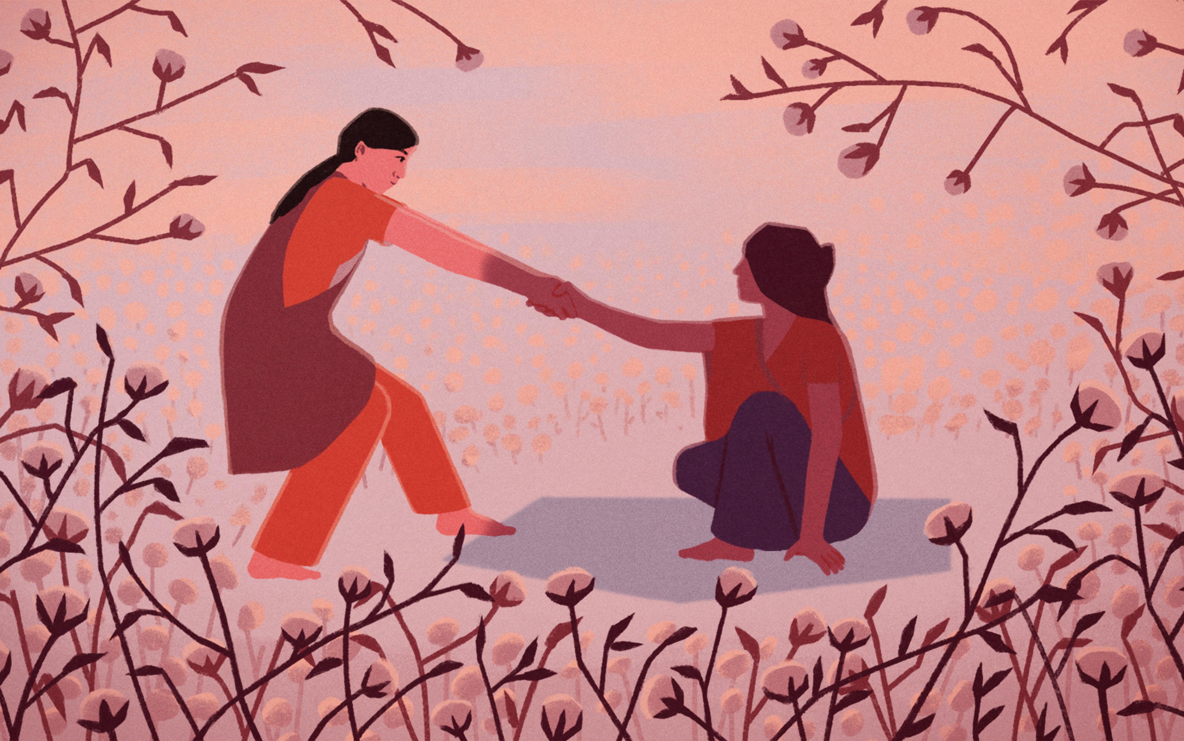A woman helps another woman to her feet in a clearing among flowers.
