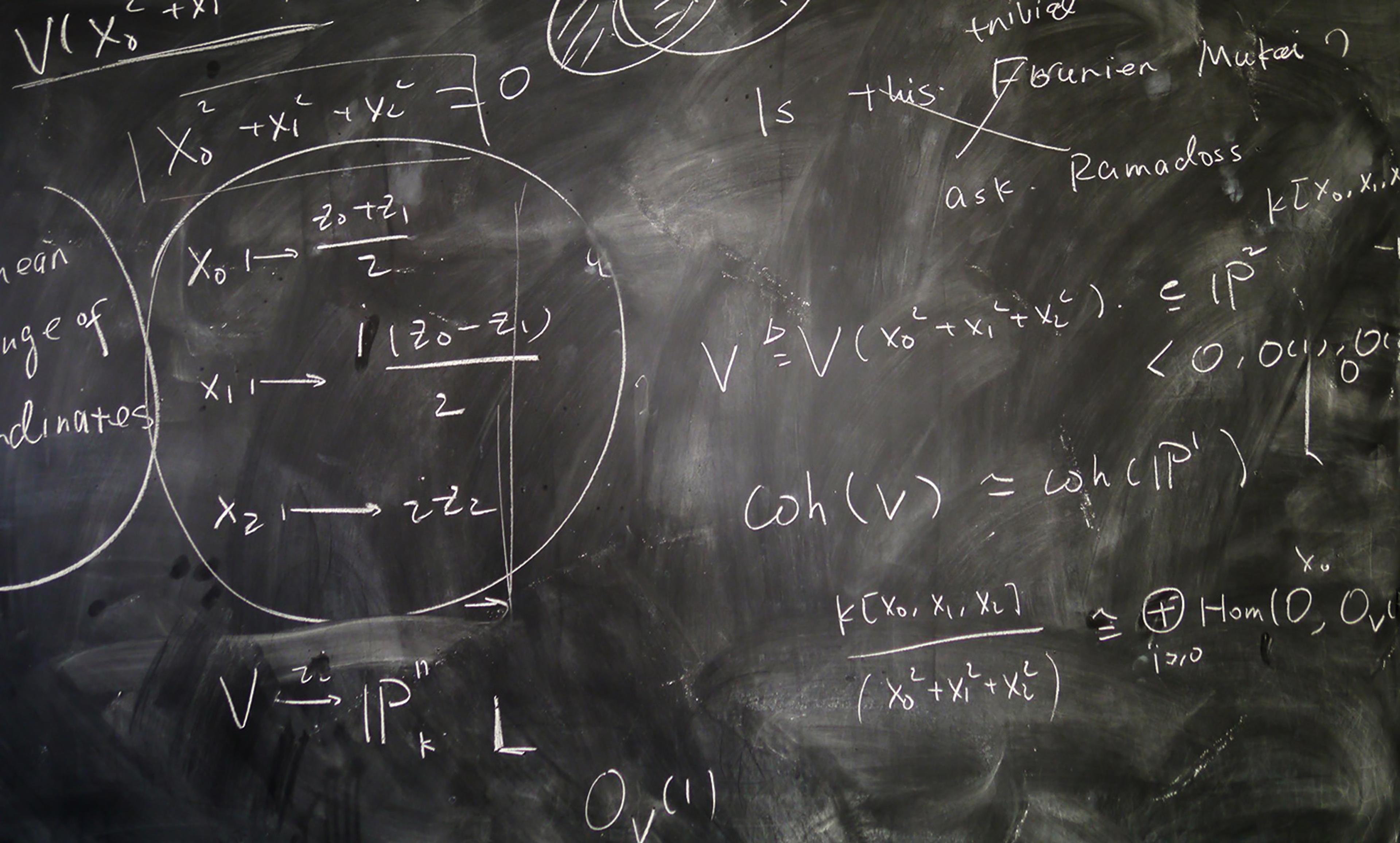 A blackboard filled with various mathematical equations, symbols and diagrams written in white chalk.