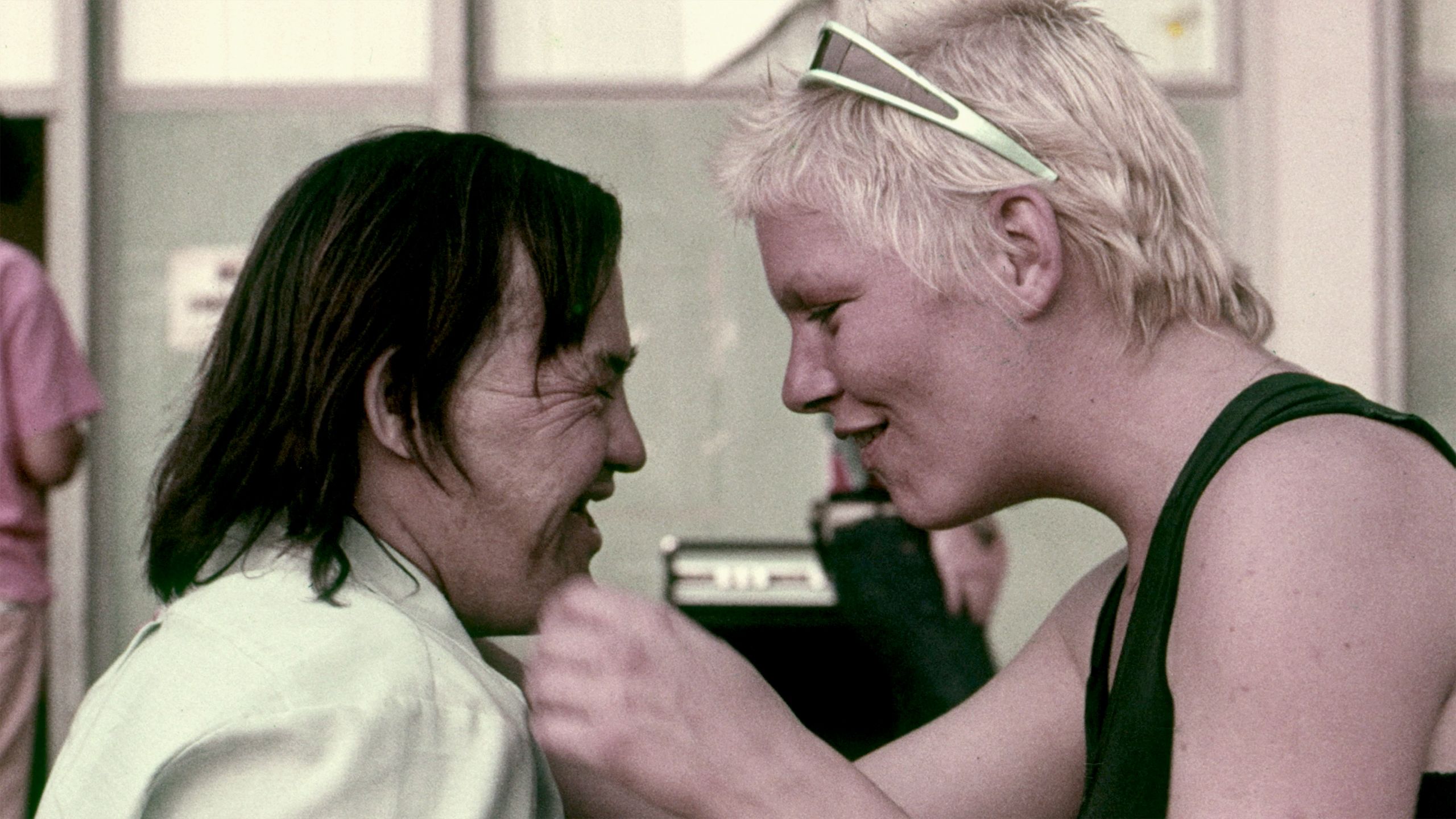 Photo of two people facing each other closely with expressions of joy in a casual setting.