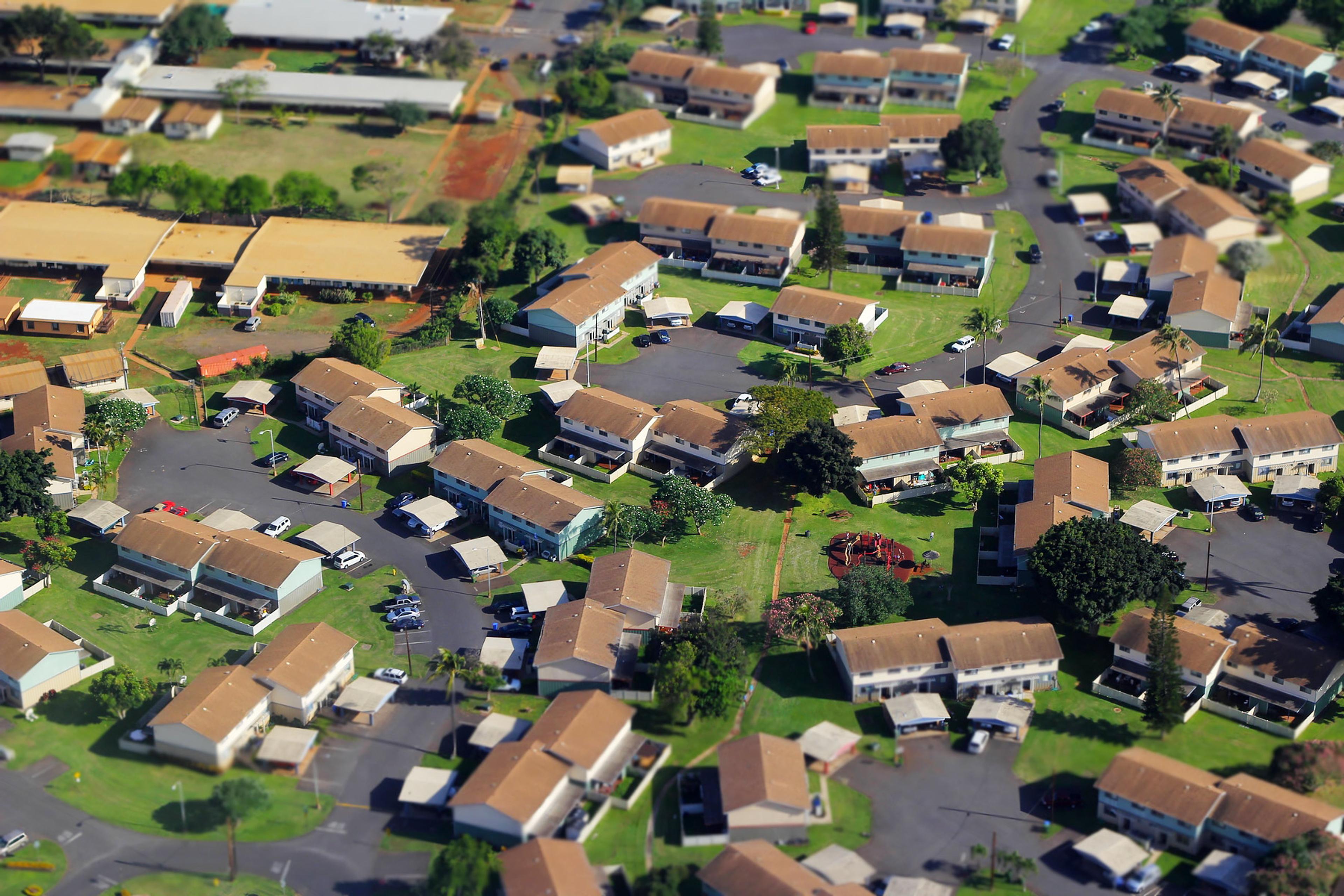Aerial photo of a suburban neighbourhood with neatly arranged houses, green lawns, cars parked and a playground.