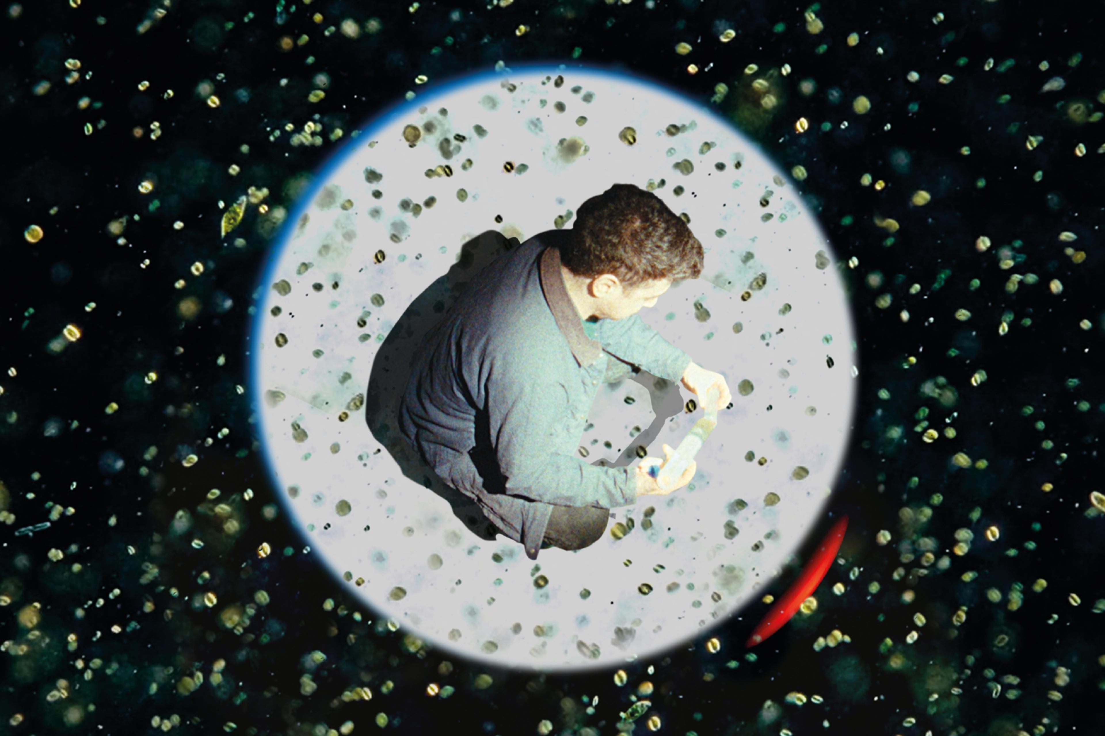 Photo of a man sitting in a circle on a speckled background, focusing on an object in his hands, with a cosmic effect.
