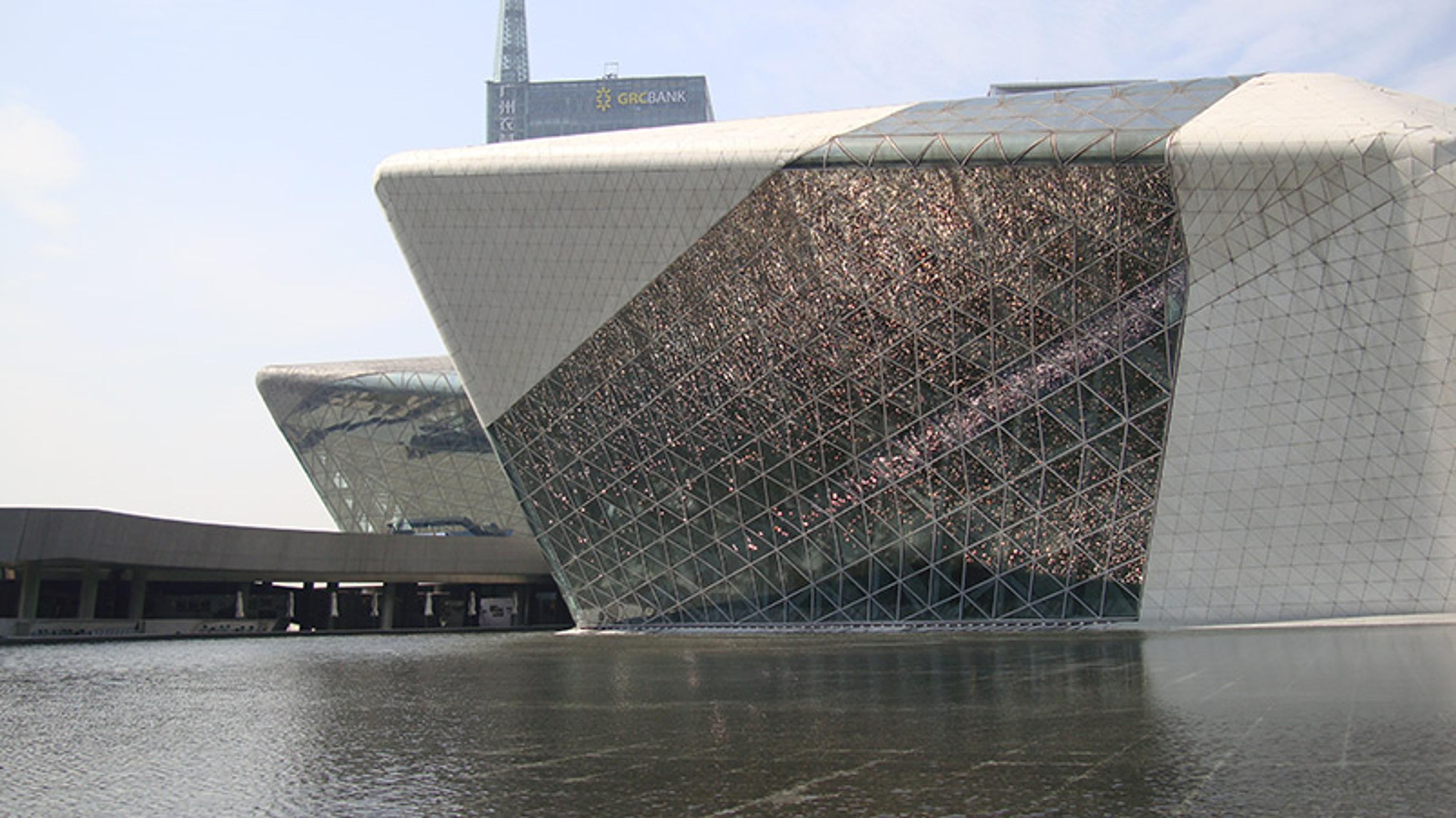 A modern architectural building with a unique geometric design next to a body of water on a clear day.