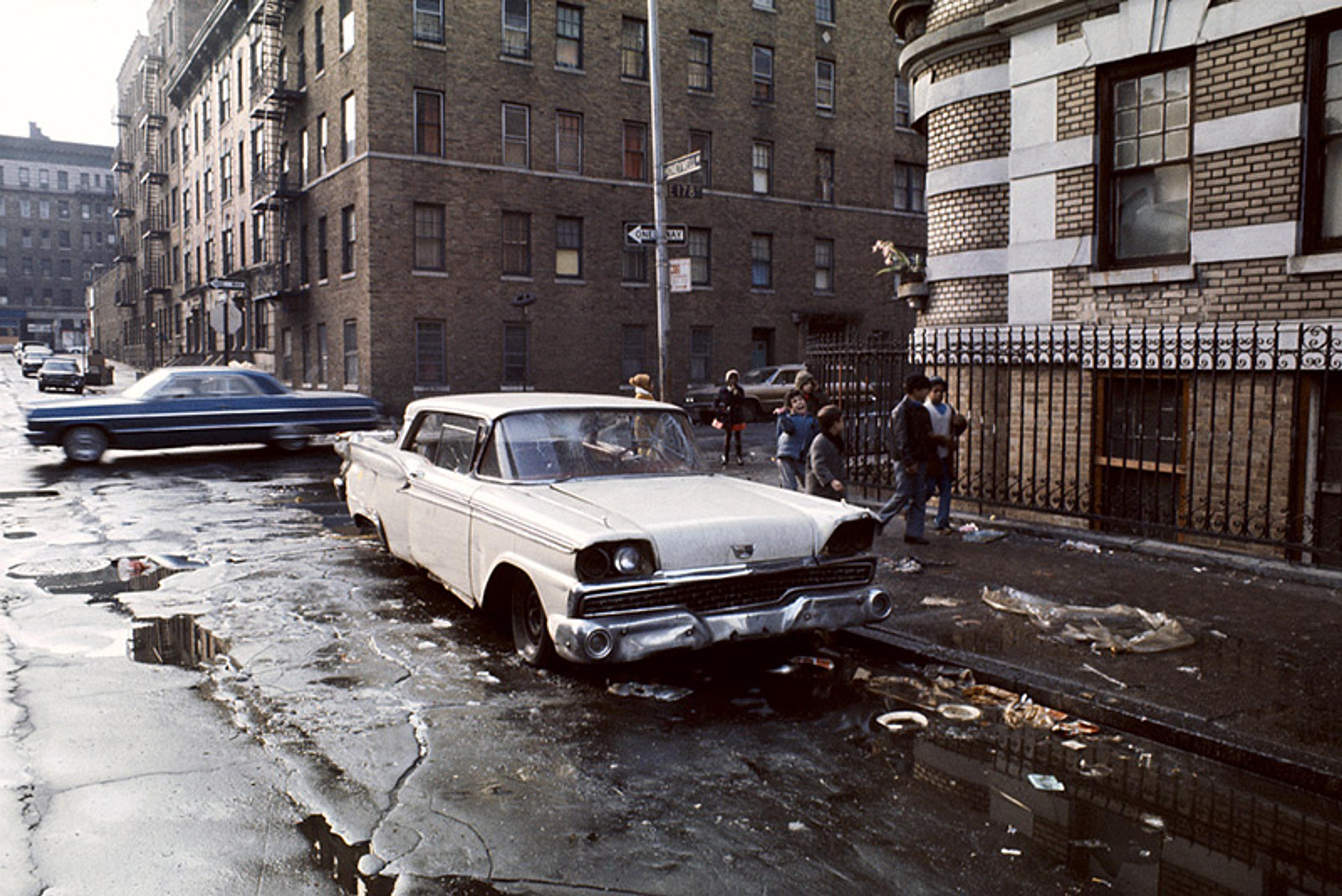 Abandoned cars on a rubbish-strewn urban street