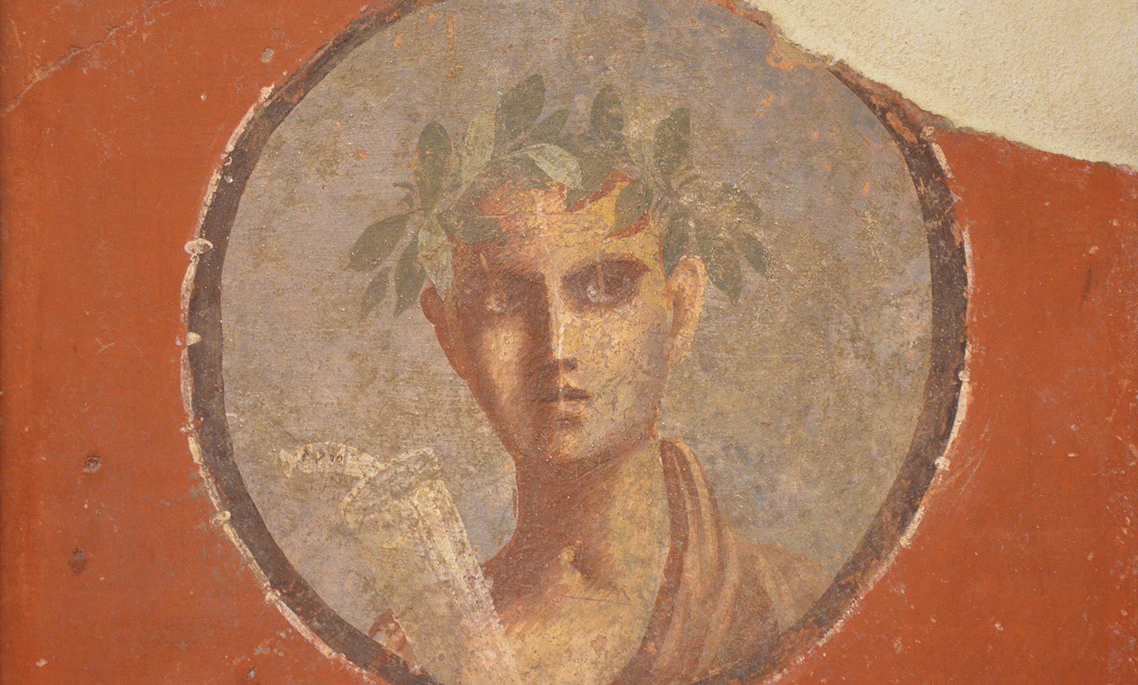 Ancient Roman fresco of a figure wearing a laurel wreath, holding a scroll, set inside a circular frame on a red background.