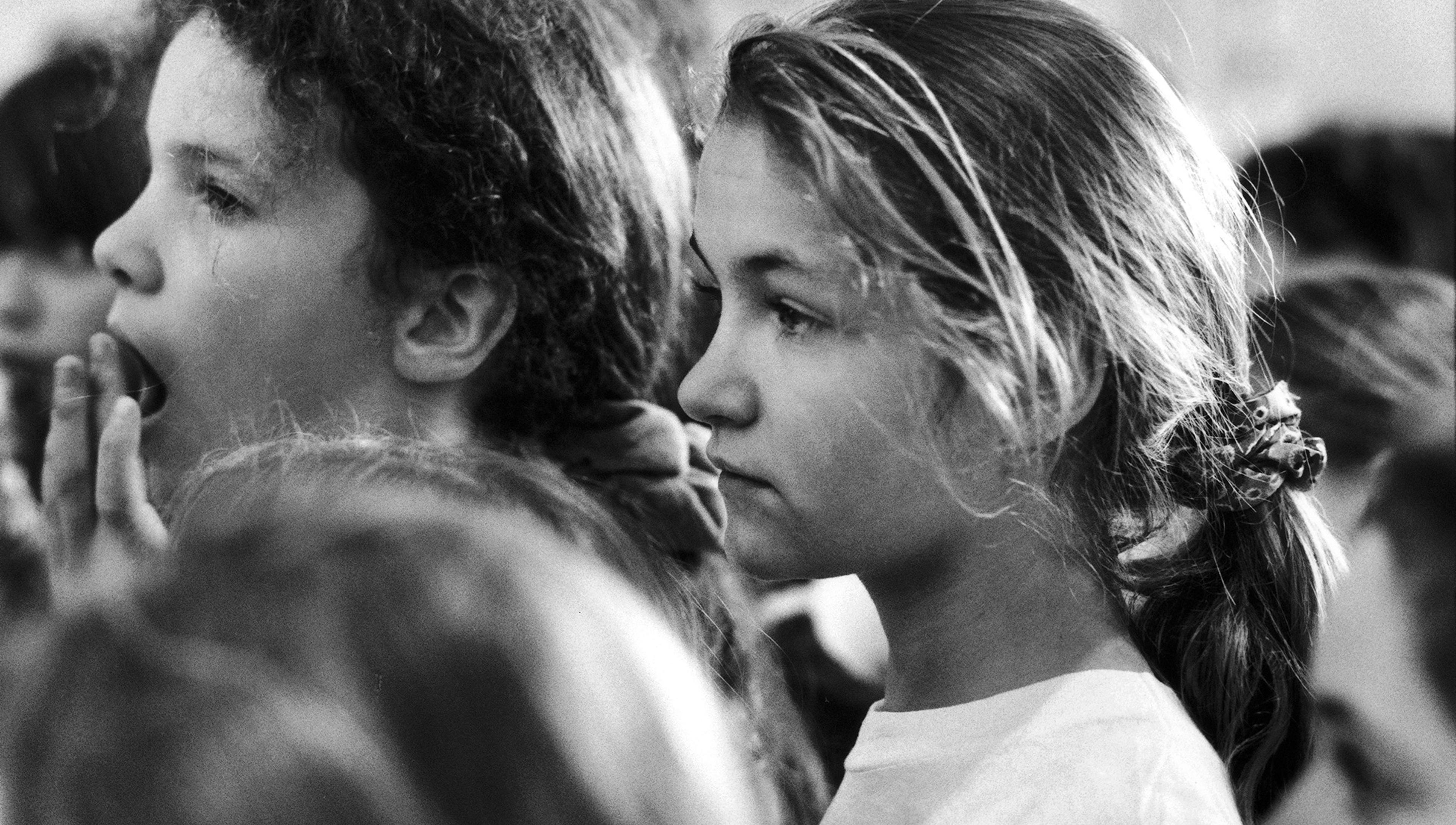 Black-and-white photograph of two girls, one yawning and the other looking forward, both in close-up profile.