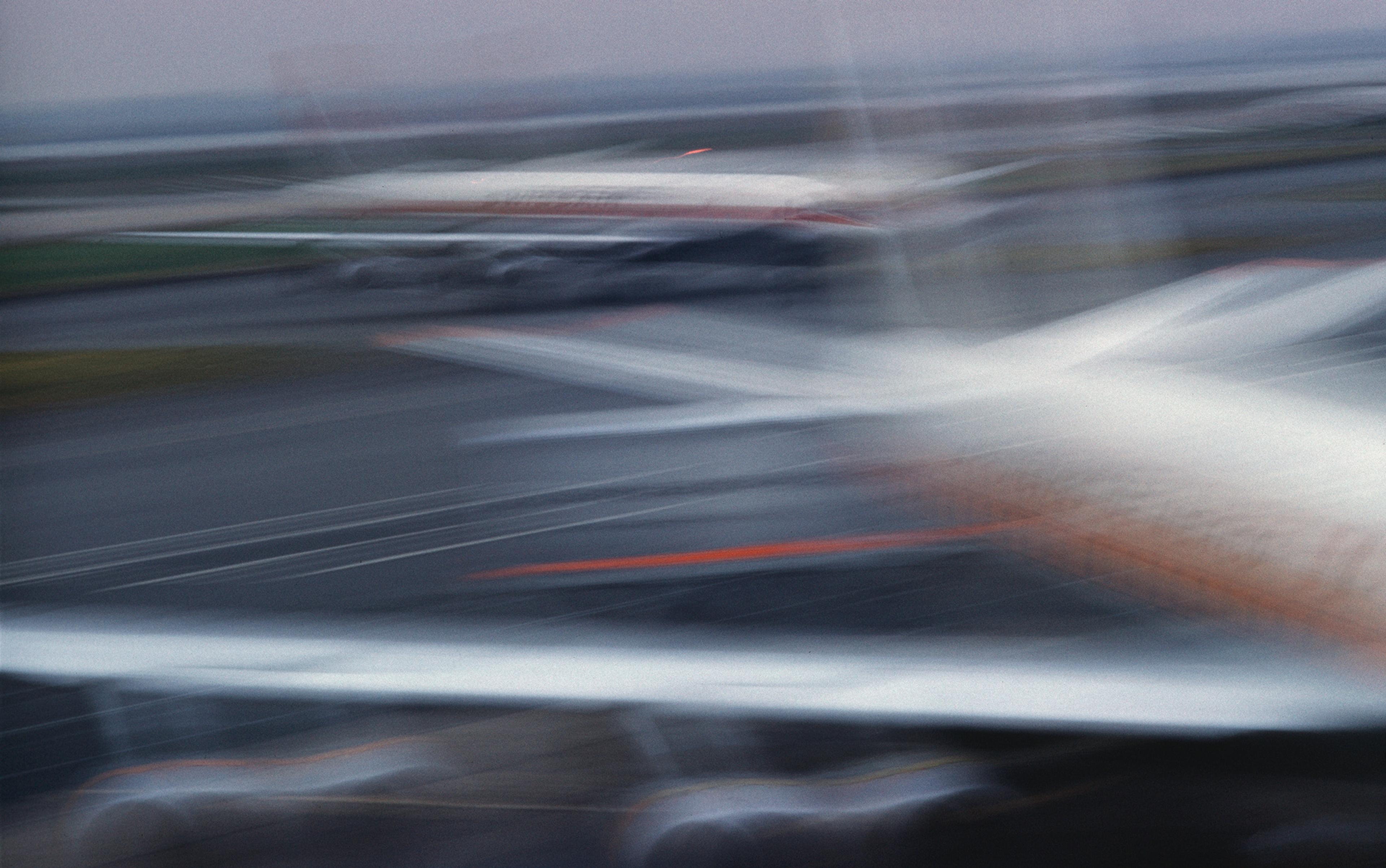 Blurry image of aeroplanes at an airport, with a hazy, indistinct look and soft, streaked lines suggesting motion or low light.