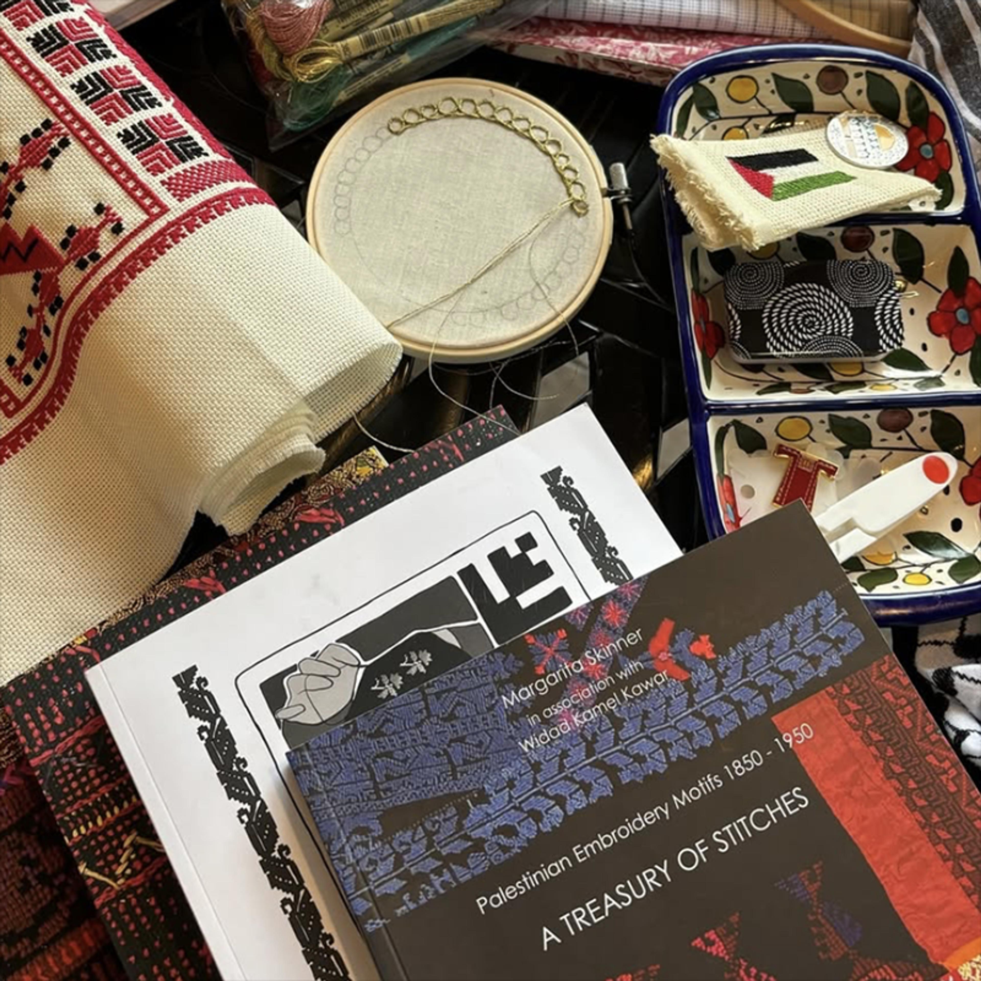 Photo of embroidery supplies and books on Palestinian motifs, with thread, fabric and a dish with compartments.