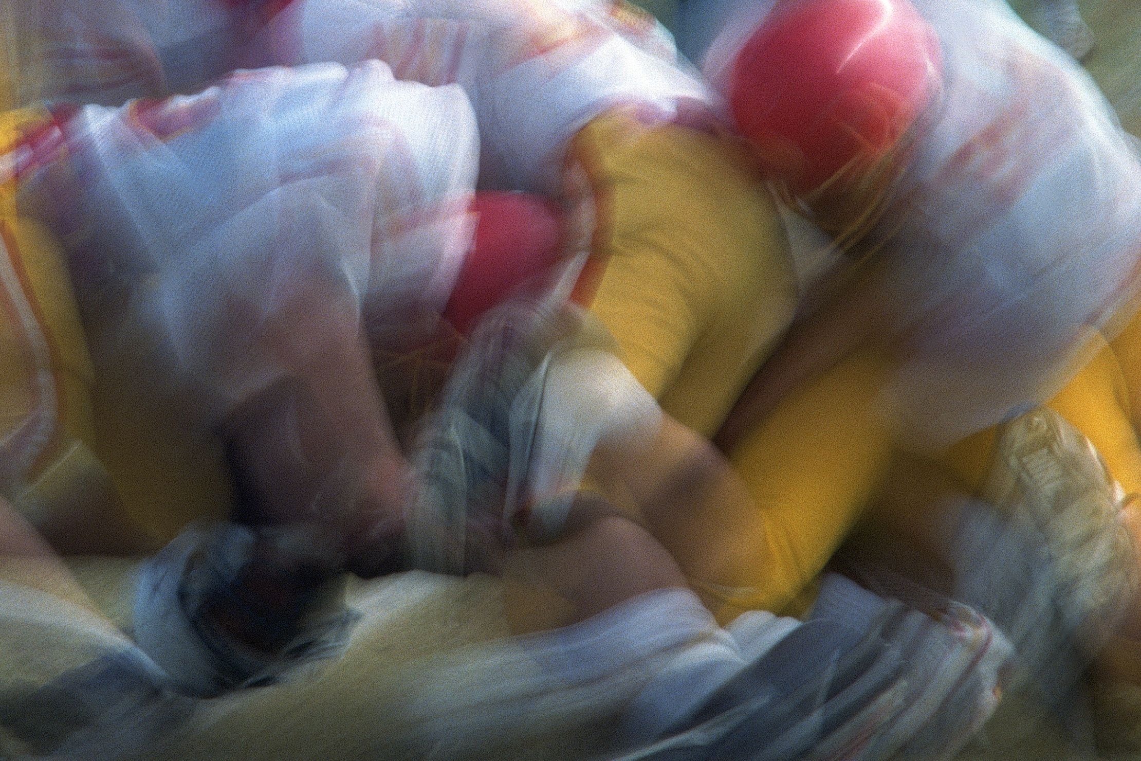 Blurred photo of American football players in red and yellow uniforms in motion during a game.