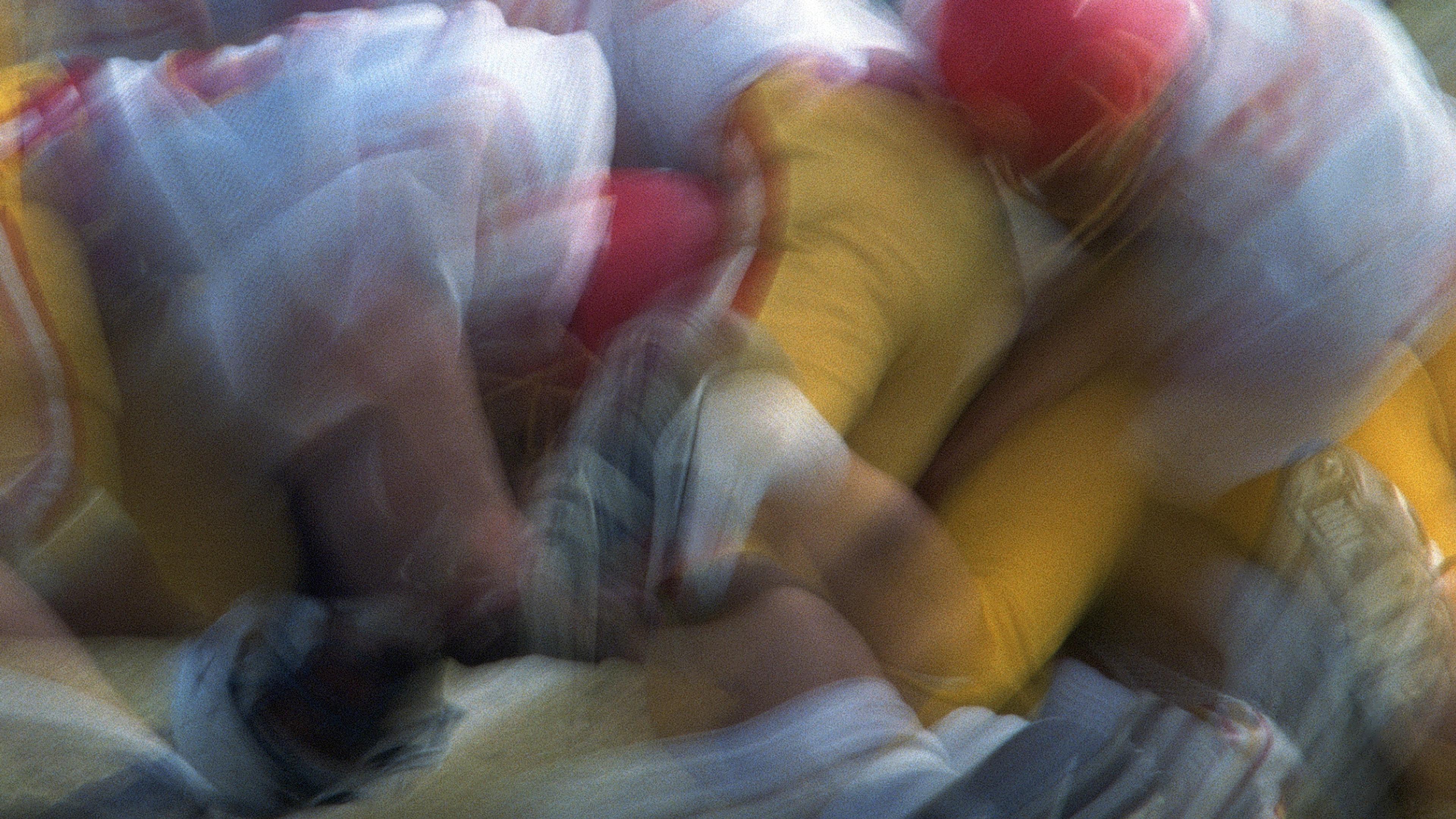 Blurred photo of American football players in red and yellow uniforms in motion during a game.