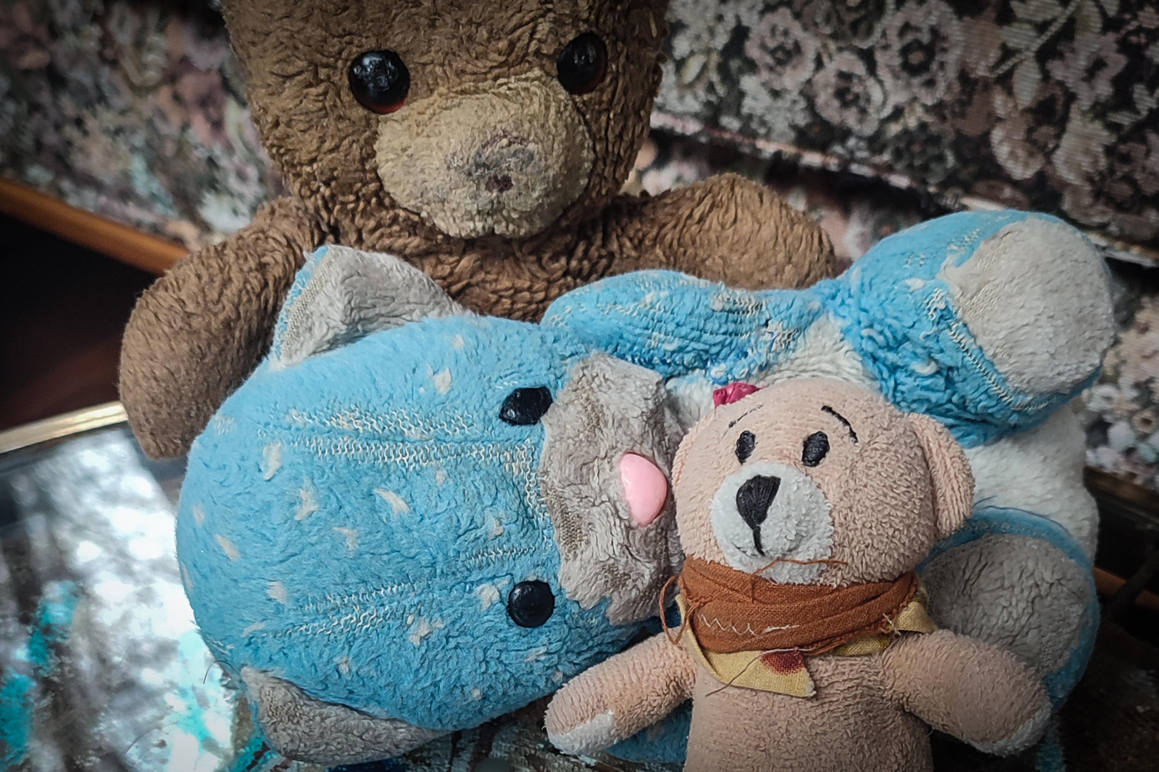 Three worn teddy bears, one beige, one blue and a brown one that has had its nose rubbed off.