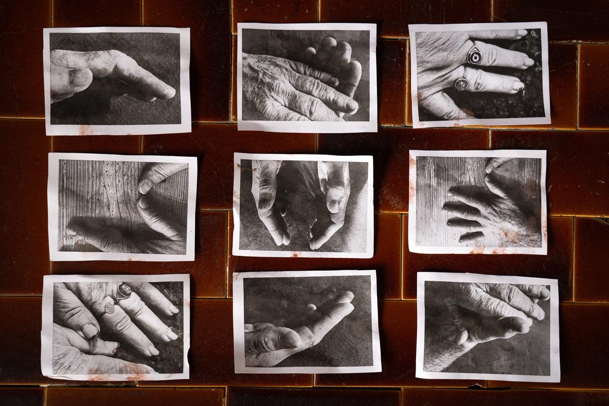 Black and white photos of hands arranged in a grid on a dark brown tiled wall.
