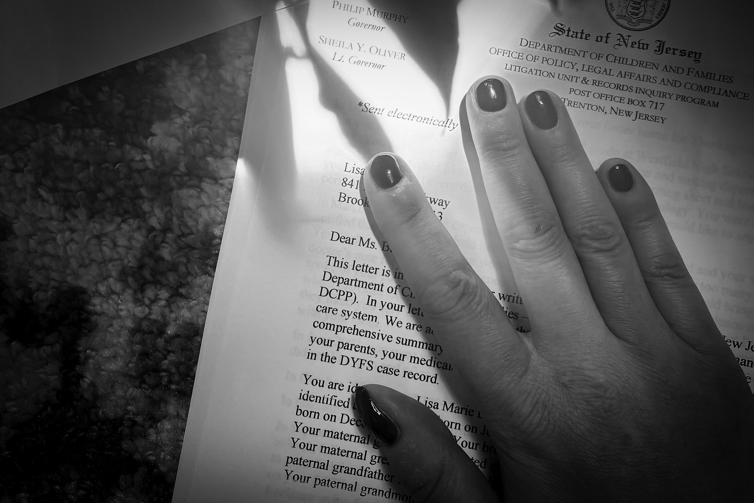 Black and white photo of a hand on a letter from the State of New Jersey Department of Children and Families.