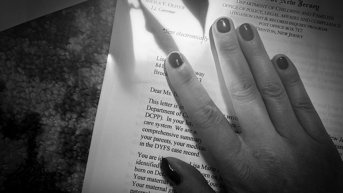 Black and white photo of a hand on a letter from the State of New Jersey Department of Children and Families.