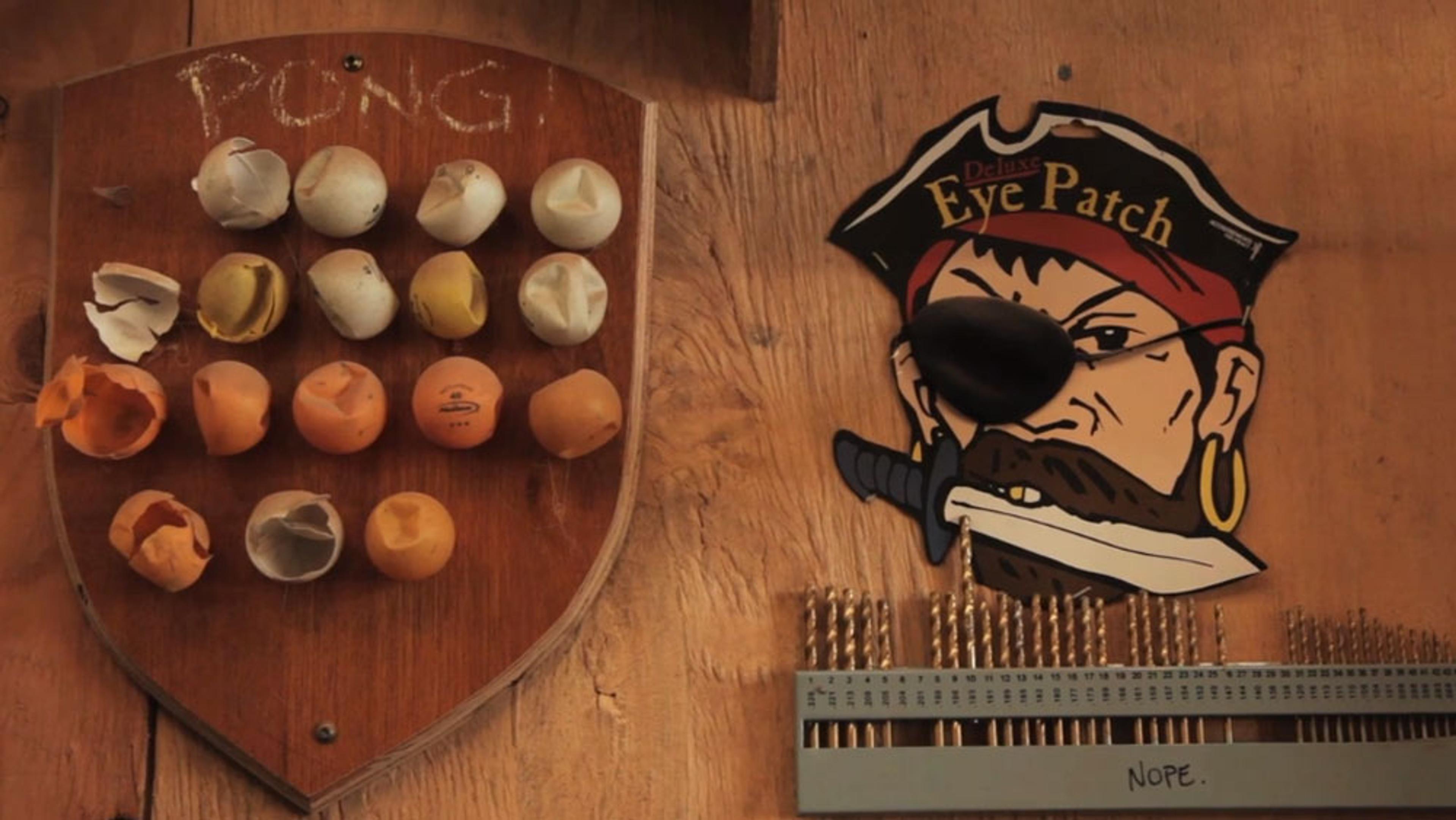 A wooden wall with a shield holding ping pong balls, a pirate face with an eye patch and drill bits labelled “NOPE”.