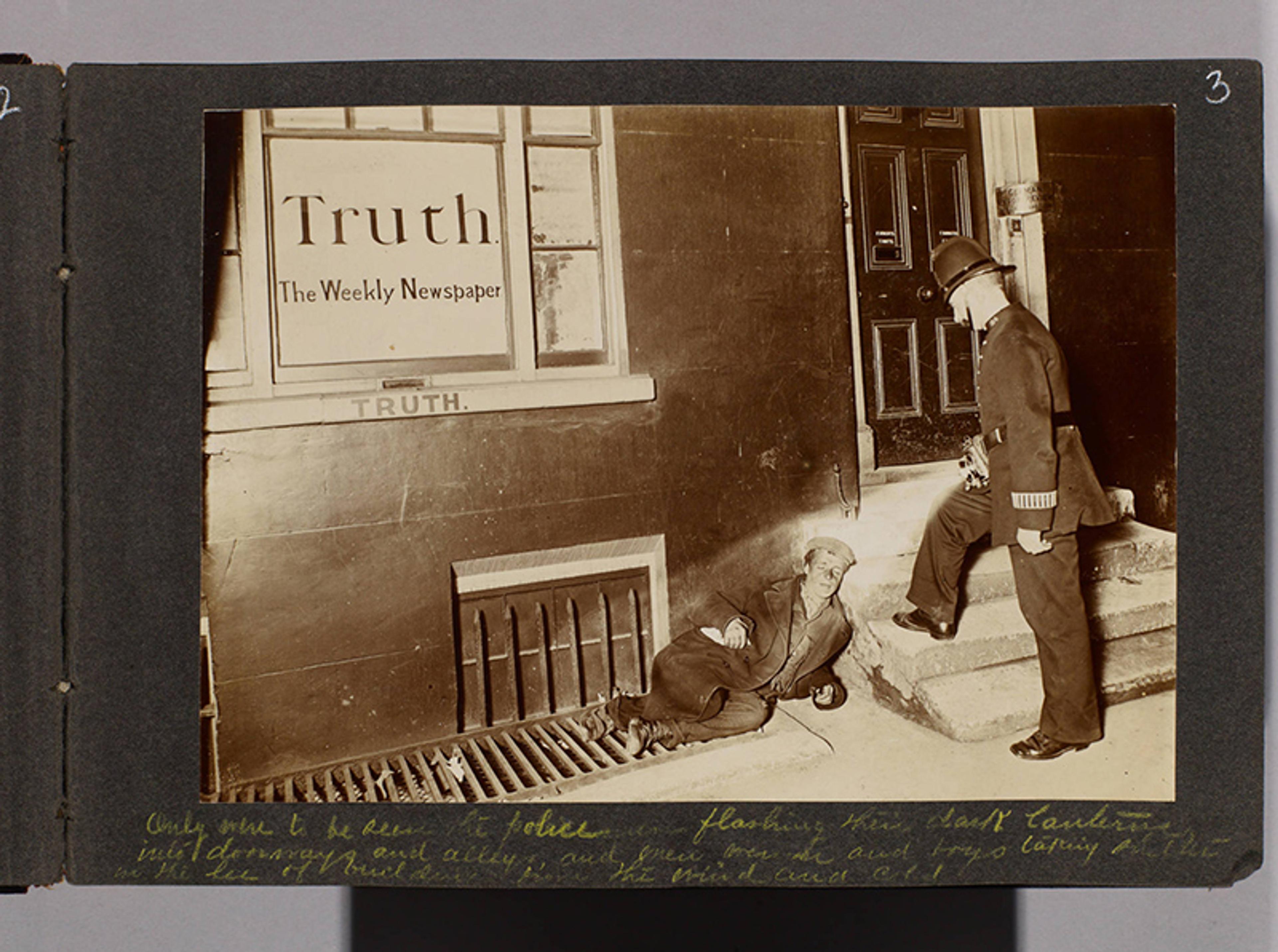 Sepia-toned photo of a man lying on the ground beside steps outside a building marked “Truth The Weekly Newspaper” with a policeman nearby.