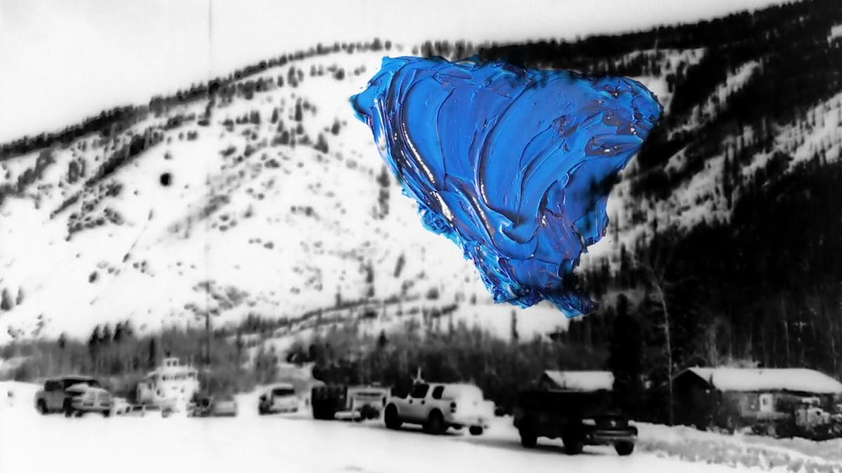 Black and white snowy mountain scene with vehicles, overlaid by a large smear of vivid blue paint in the upper right area.