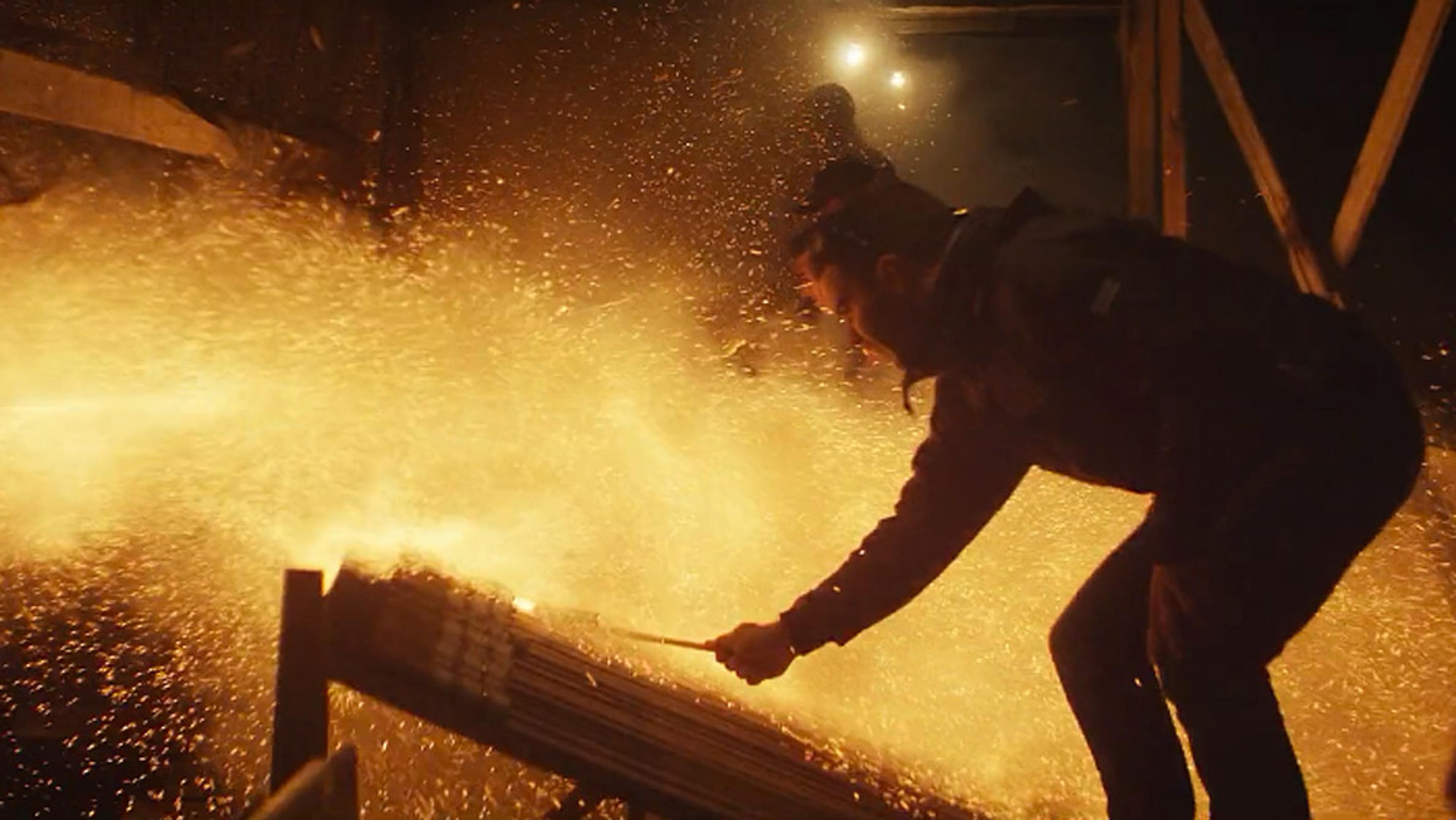 A person igniting fireworks, creating a burst of light and sparks in a dark industrial environment.