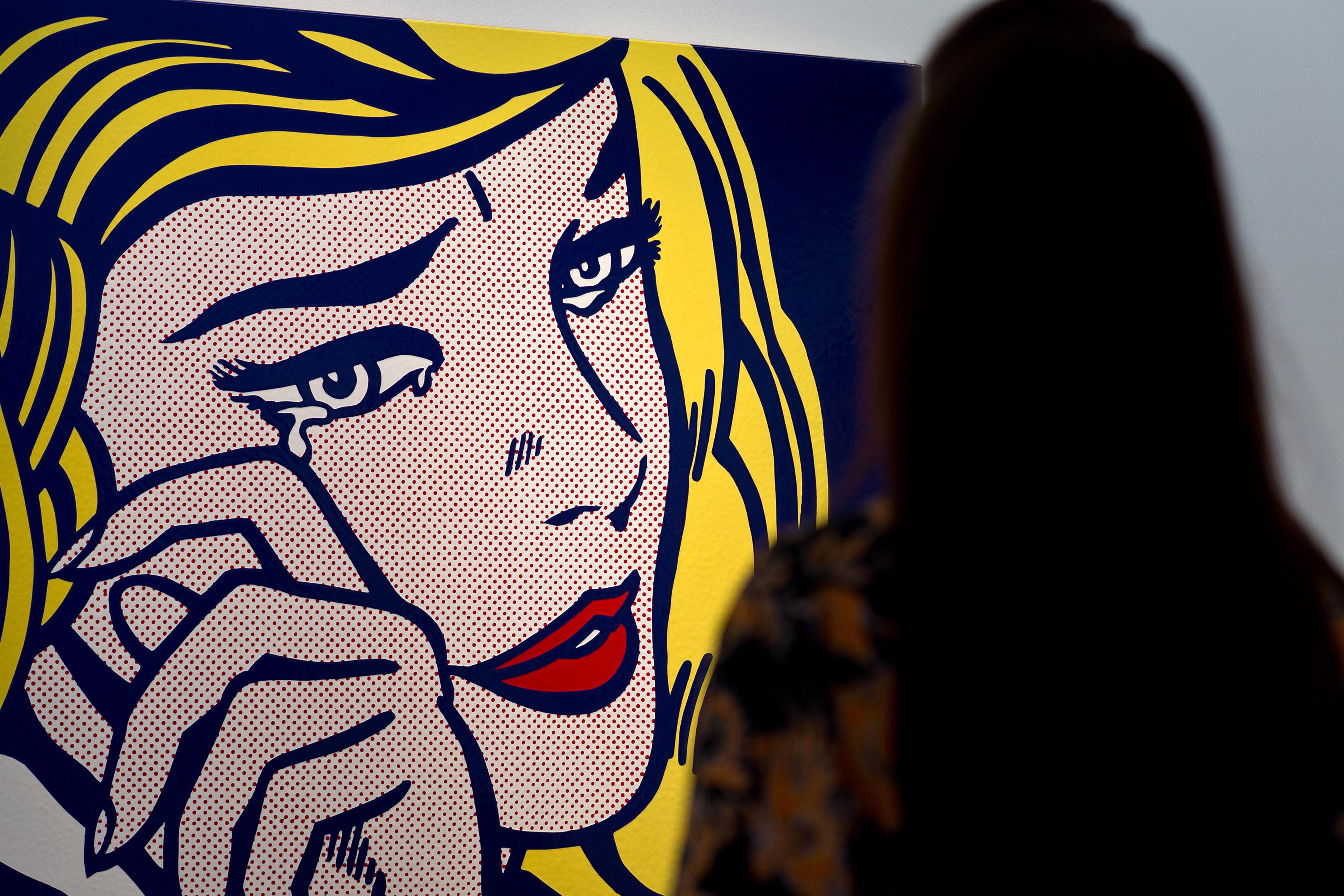 Silhouette of a person looking at a pop art painting of a crying woman.
