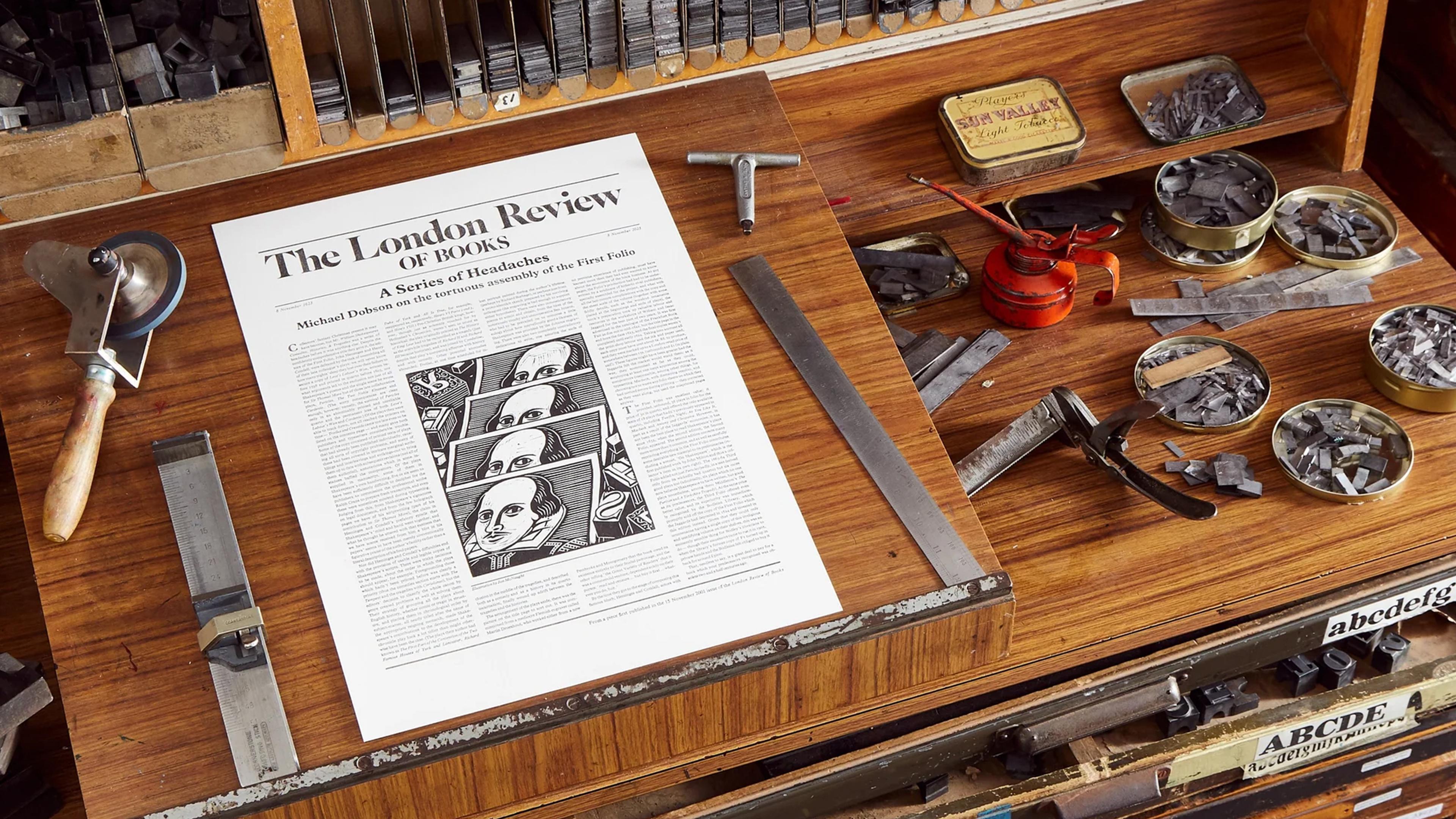 A photo of a printshop workbench featuring a newspaper layout, metal type blocks, and tools.