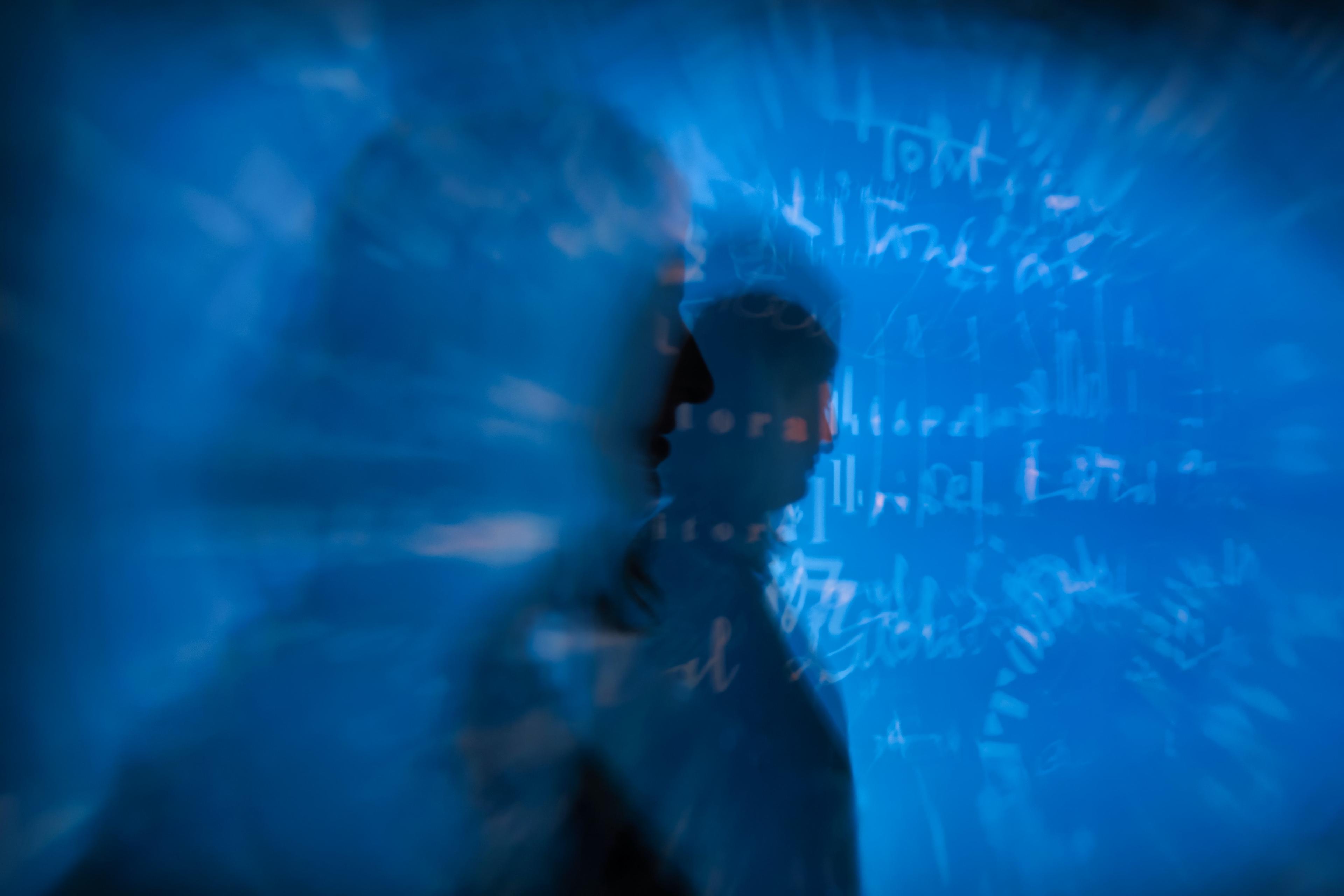 Abstract image of a silhouette against blue light with blurred text in the background, digital art.