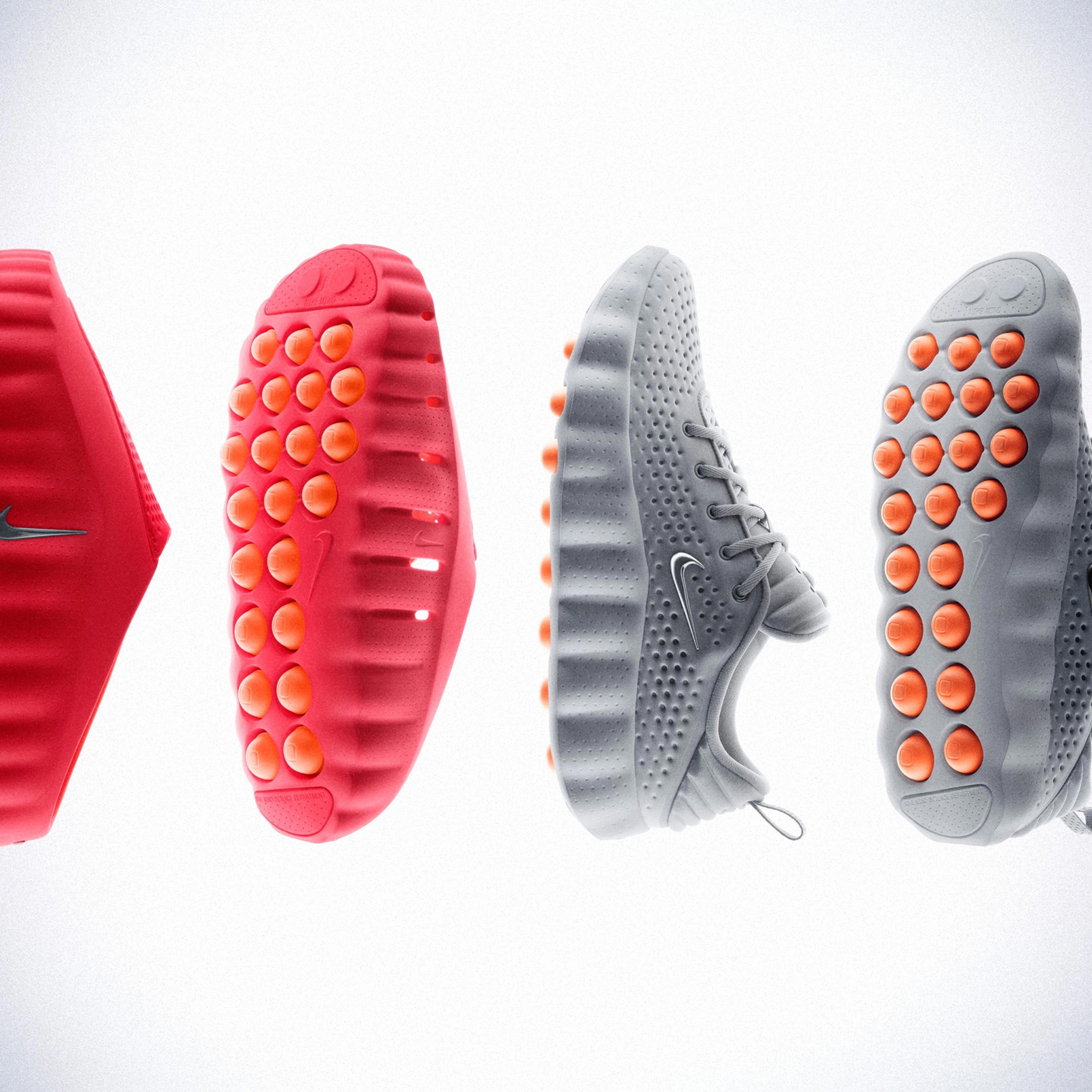 Photo of red and grey trainers levitating, showcasing textured soles with orange accents on a light background.