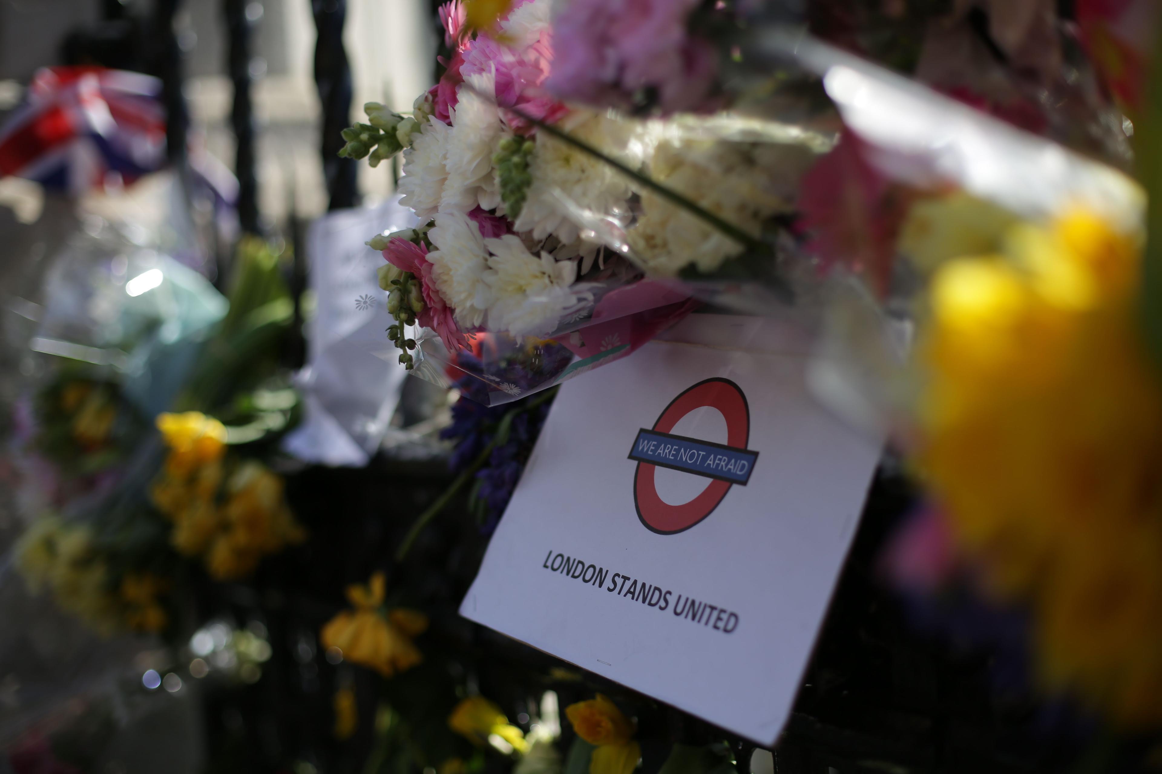 Photo of flowers with a sign reading “London Stands United” and “We Are Not Afraid” in London Underground style.