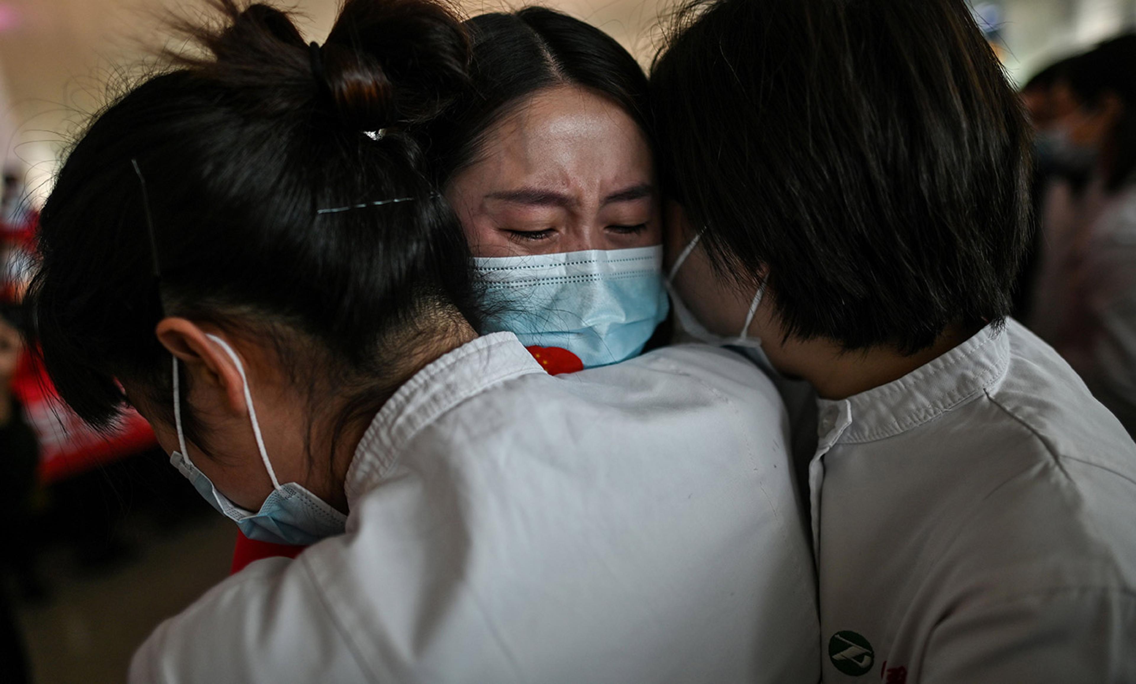 <p>Medical workers in Wuhan embrace. 8 April 2020. <em>Photo by Hector Retamal/AFP/Getty</em></p>