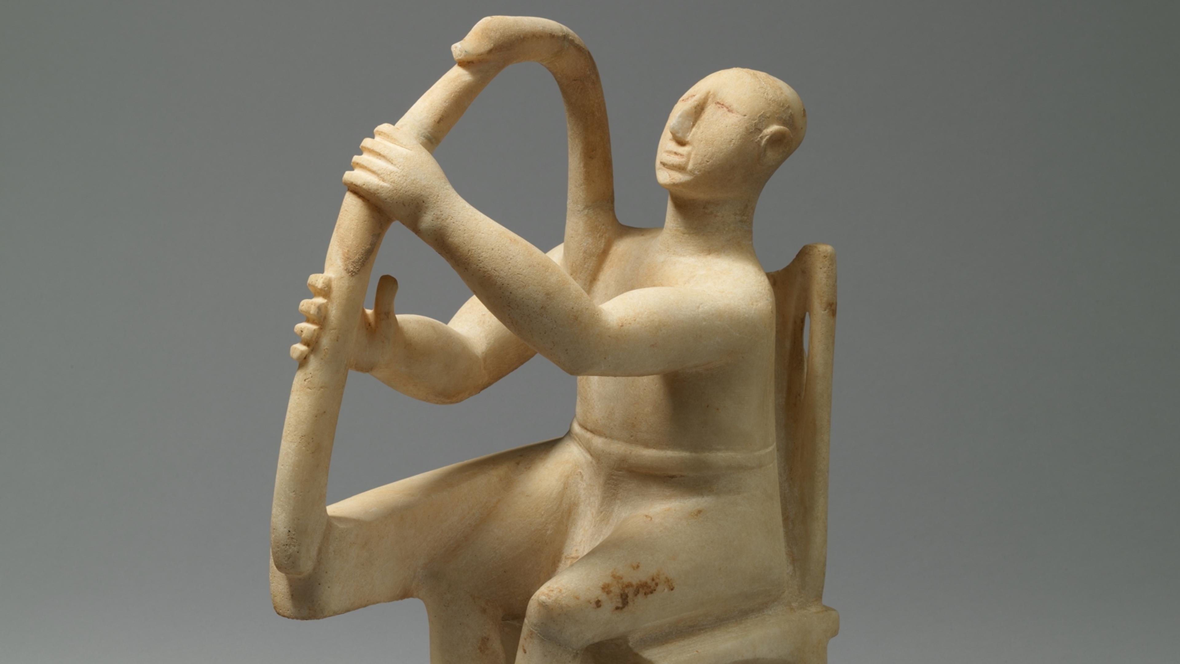 Marble sculpture of a seated figure playing a harp on a grey background.