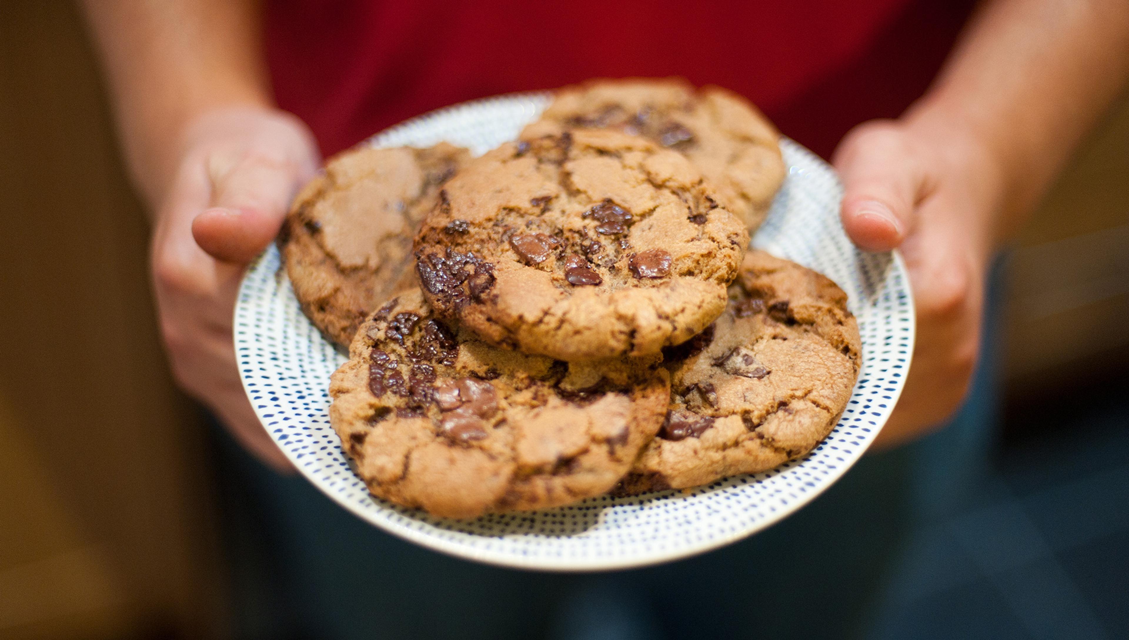 A child is offering a plate of homemade cookies