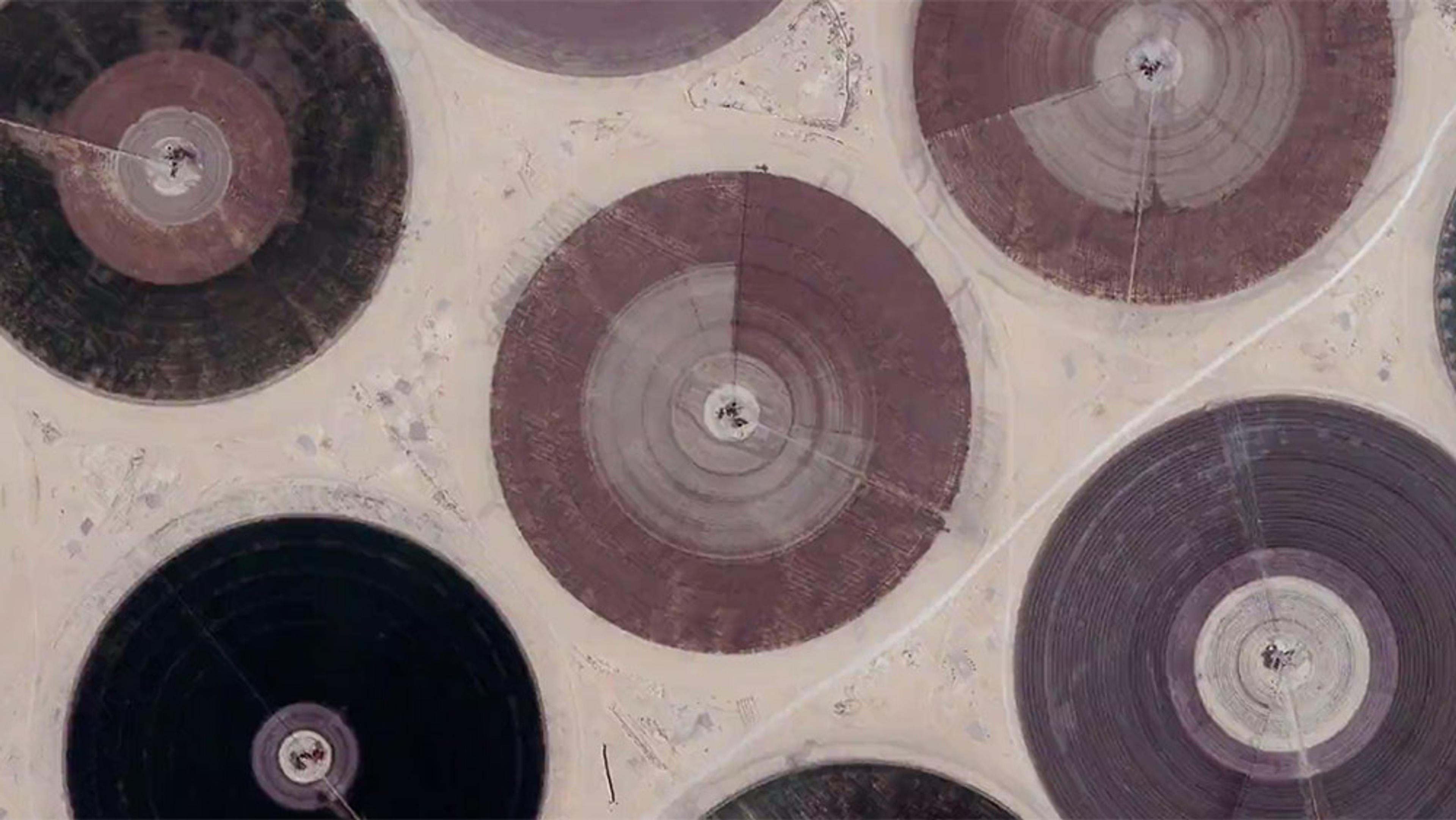 Aerial photo of crop circles in a desert, showing concentric circular fields of various colours and sizes against a sandy background.