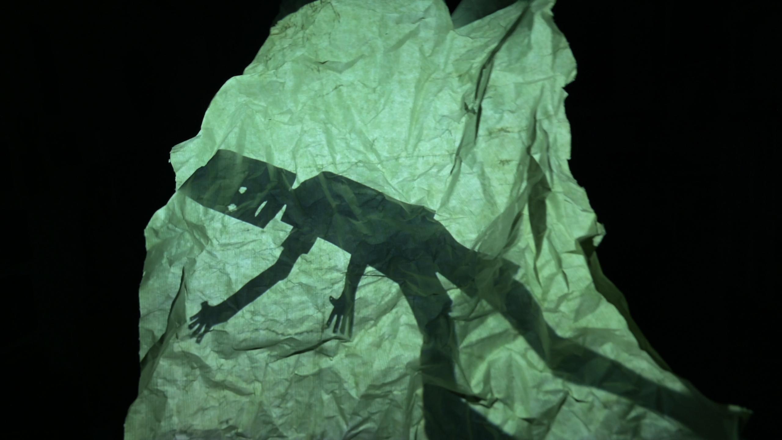 Shadow of a person on crumpled paper in dark setting photo.