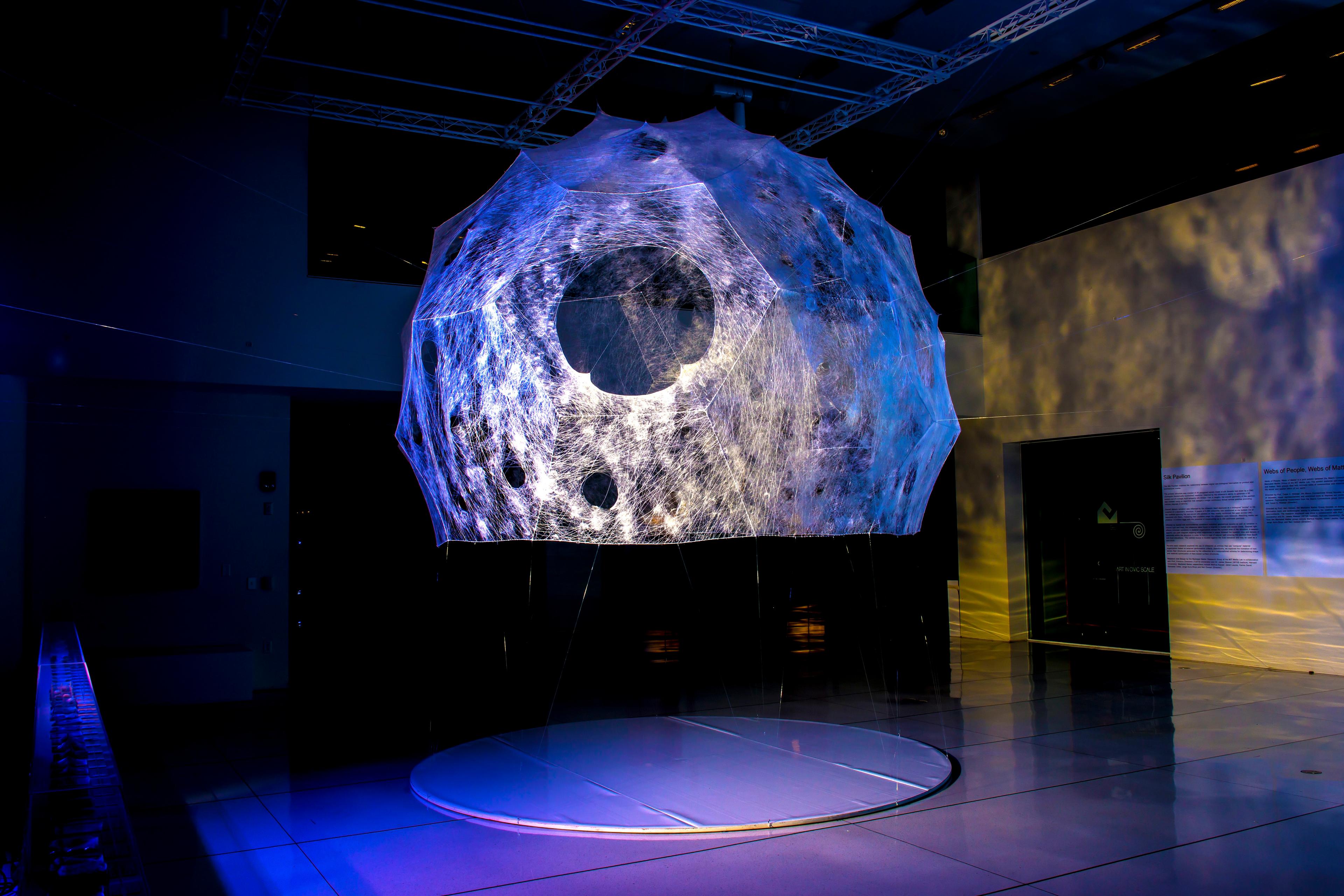Art installation of a moon sculpture with light projections in a dimly lit room.