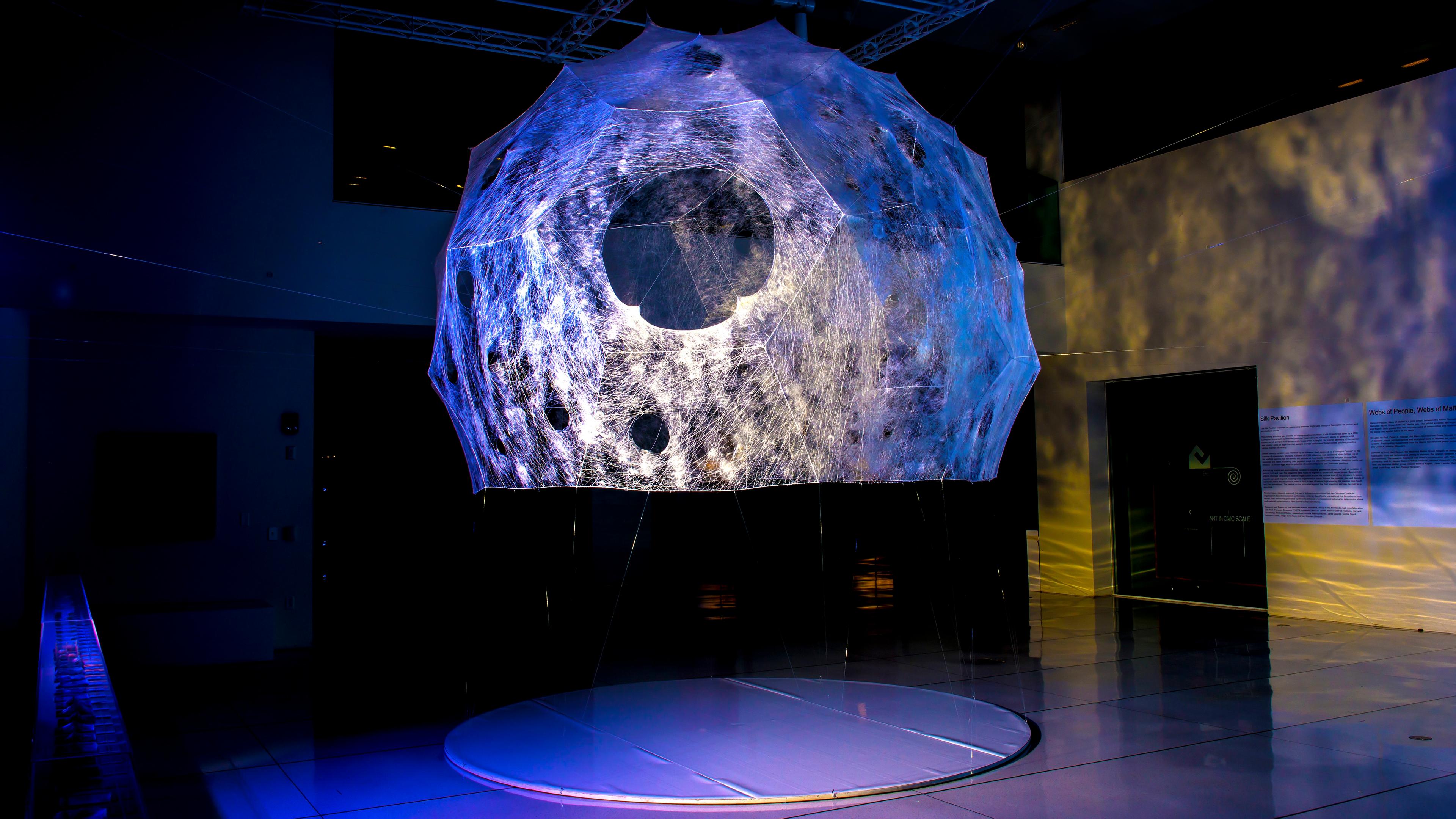 Art installation of a moon sculpture with light projections in a dimly lit room.