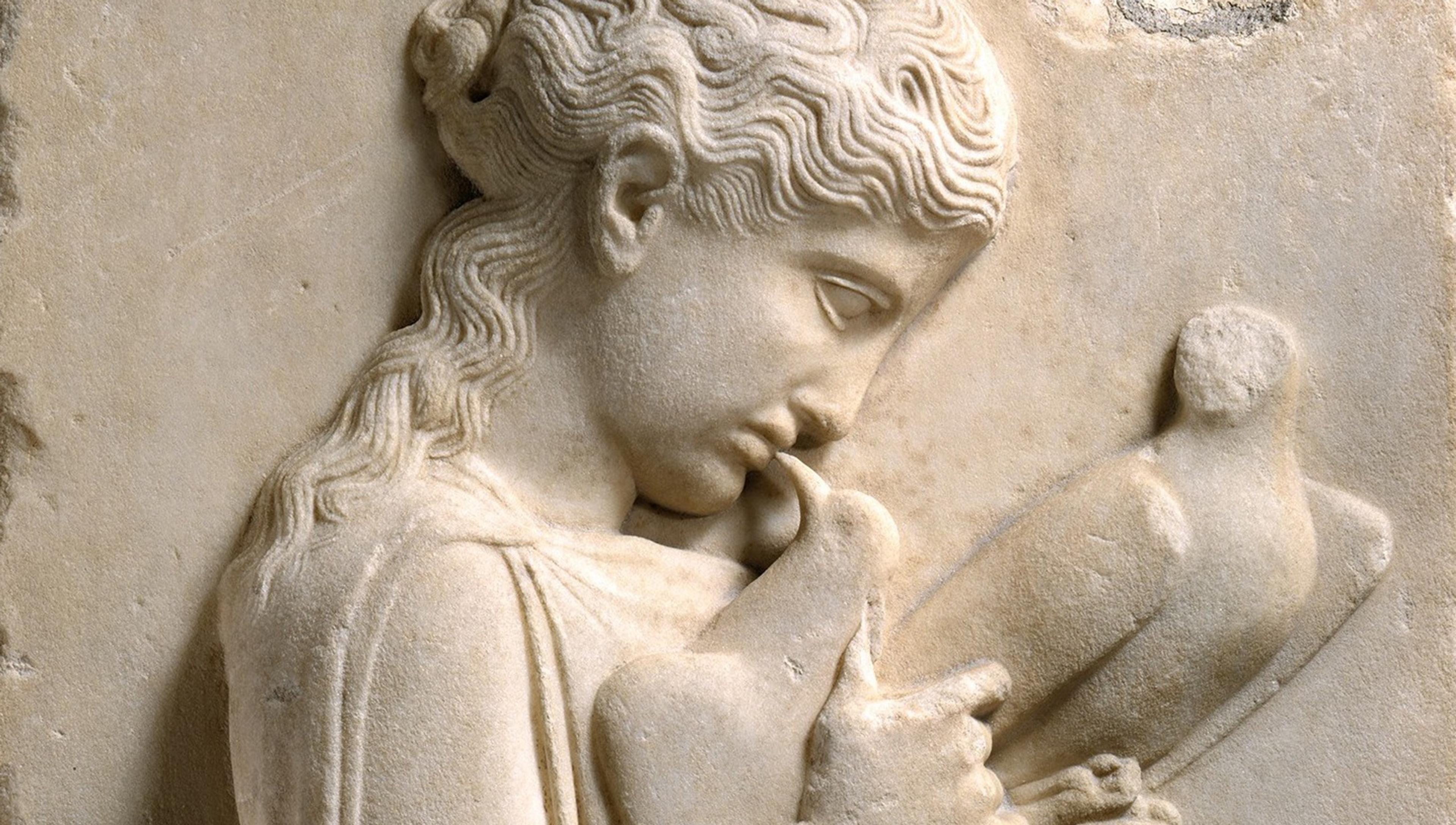 Ancient marble relief sculpture of a young girl holding a bird close to her face, with intricate detailing of her hair and clothing.