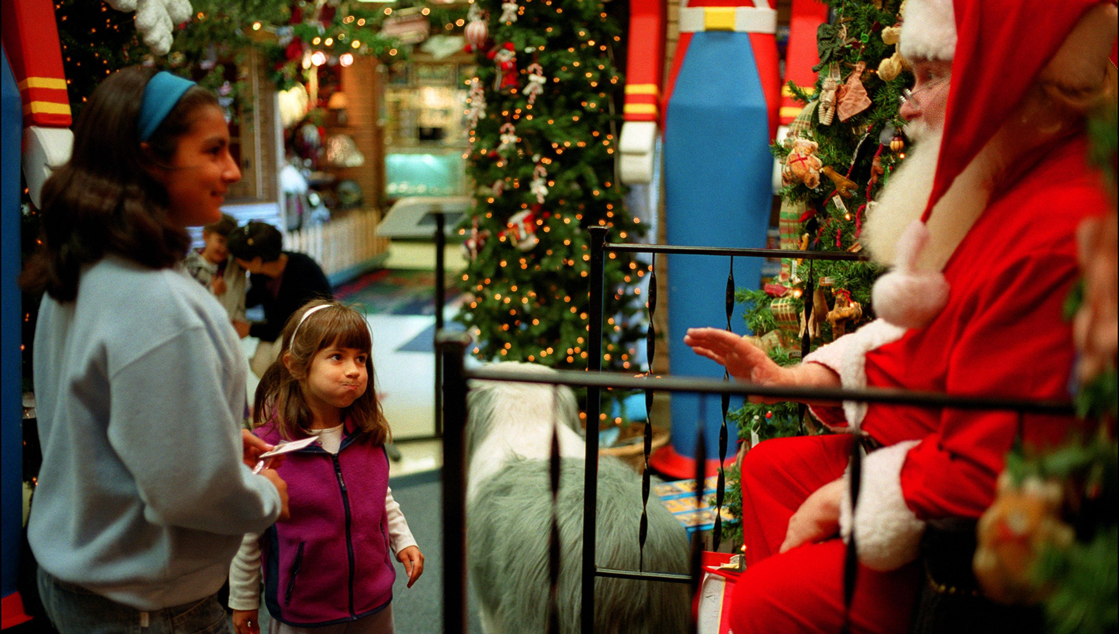 A child meeting Santa in a mall looks disbelieving