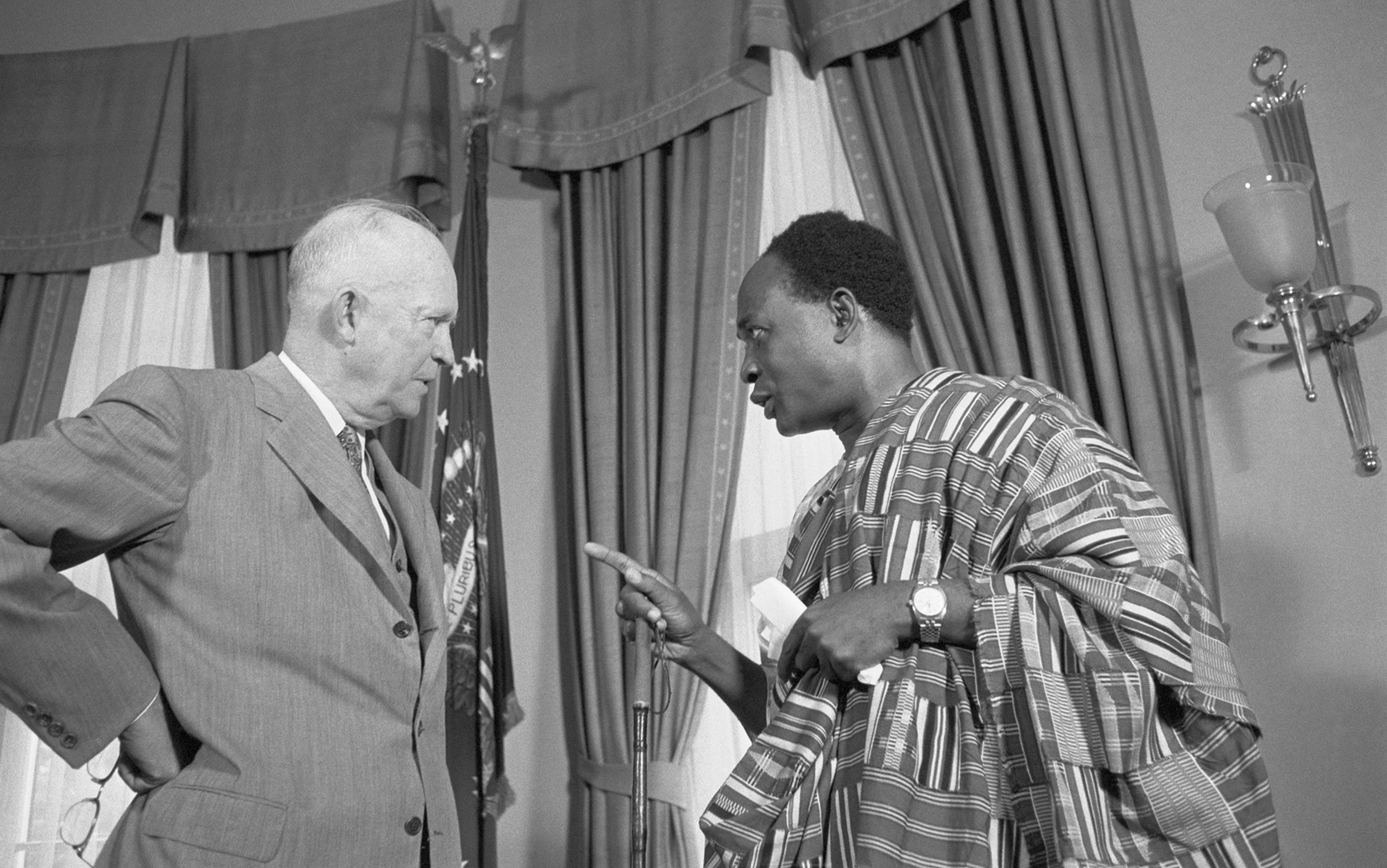 President Eisenhower and Kwame Nkrumah talking. Nkrumah is wearing traditional African attire and pointing at Eisenhower, who is wearing a suit.